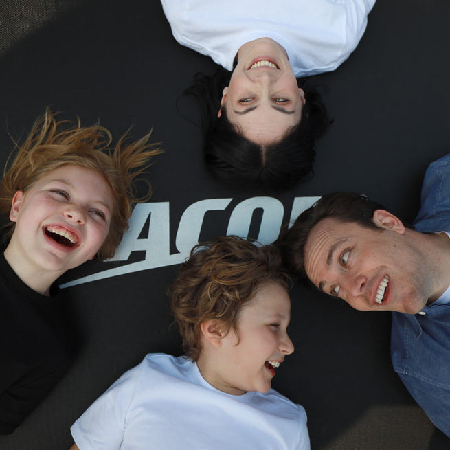 Glückliche Gesichter einer Familie, die auf dem Acon-Trampolin liegt