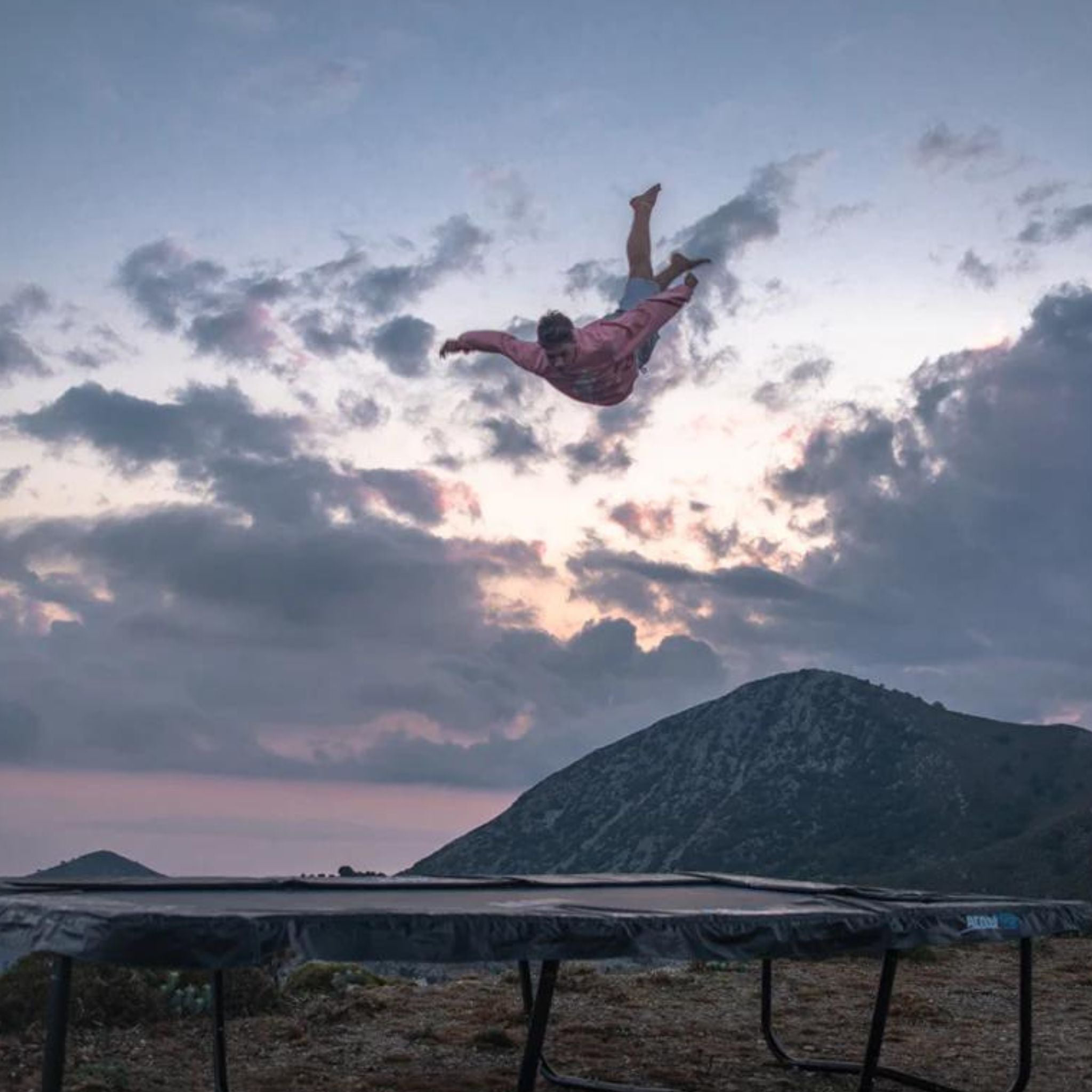 Mann hüpft Trampolin im Sonnenuntergang