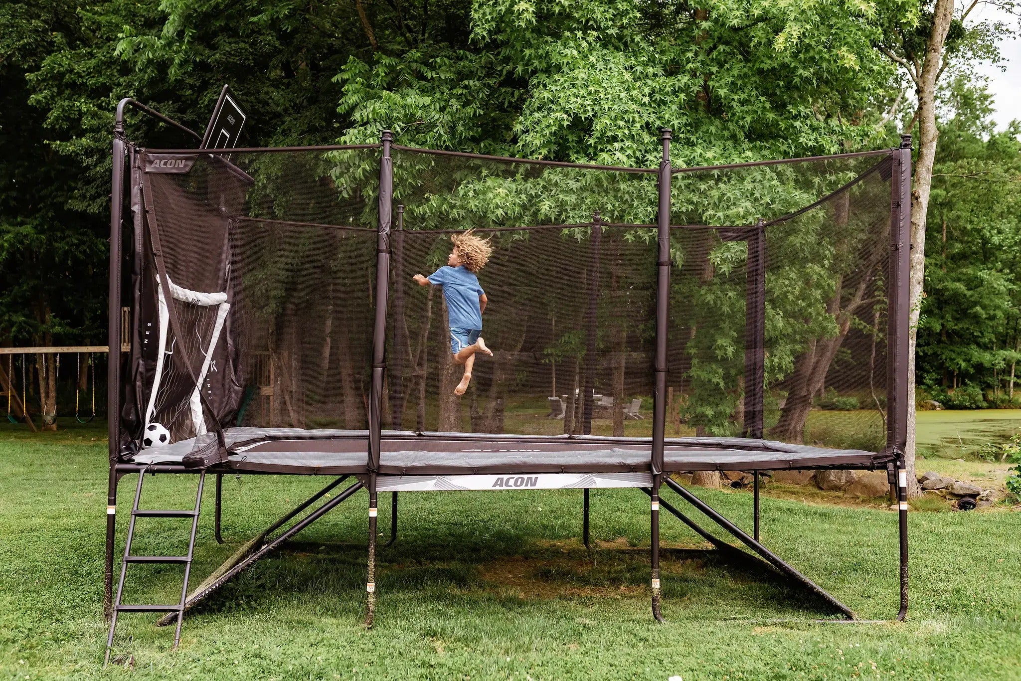 Kind springt auf einem Acon-Trampolin mit angebrachtem Fußballtor.