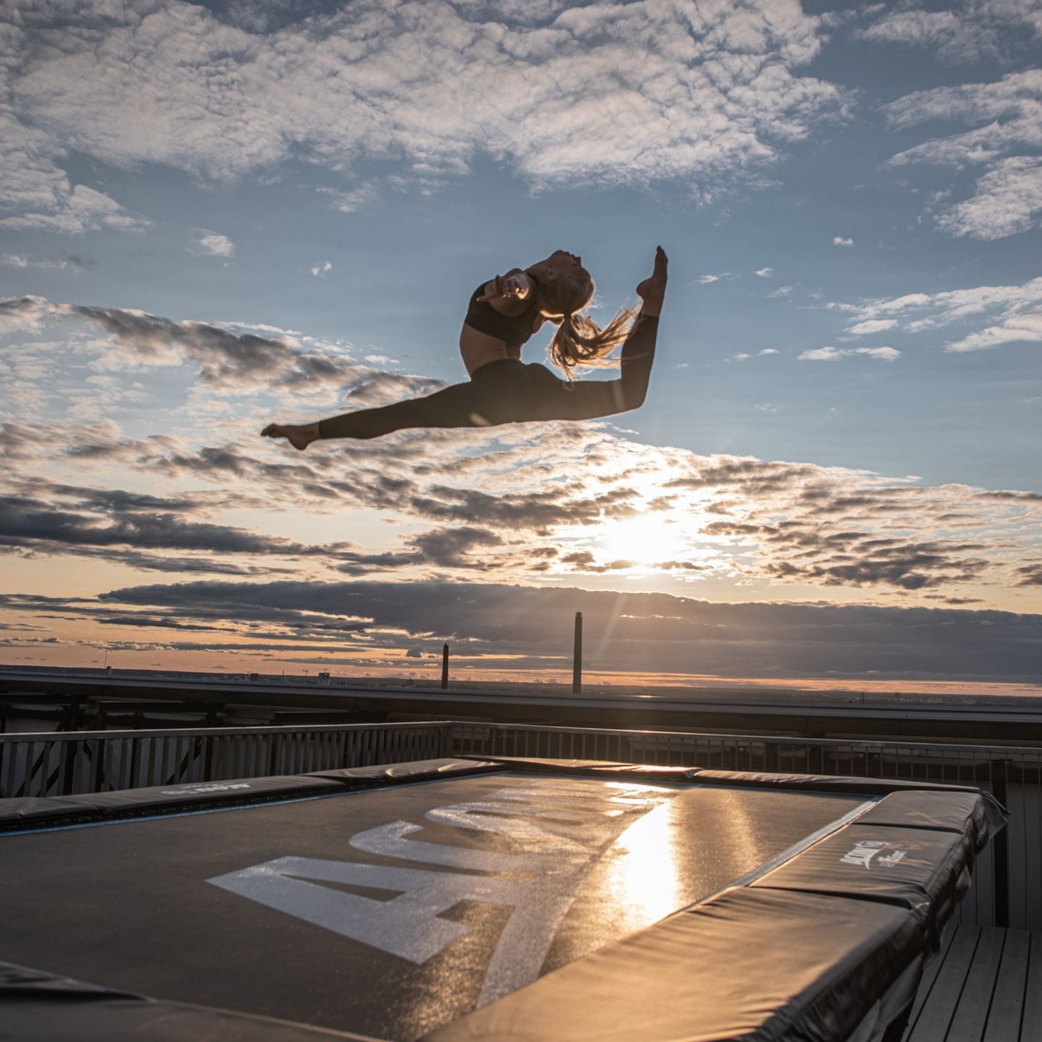 Frau trainiert auf einem ACON Trampolin im Sonnenuntergang