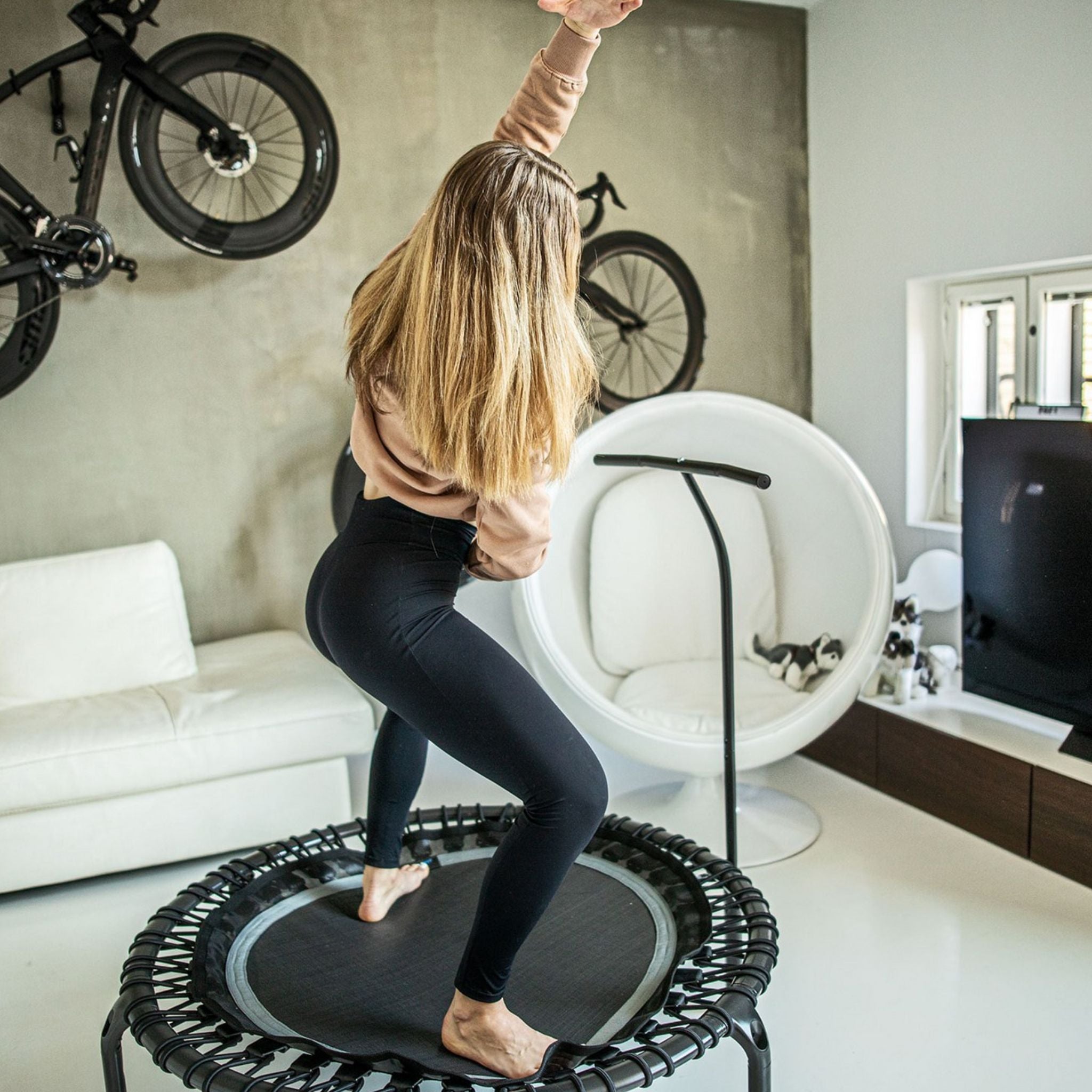 Frau trainiert auf Trampolin in ihrer Wohnung