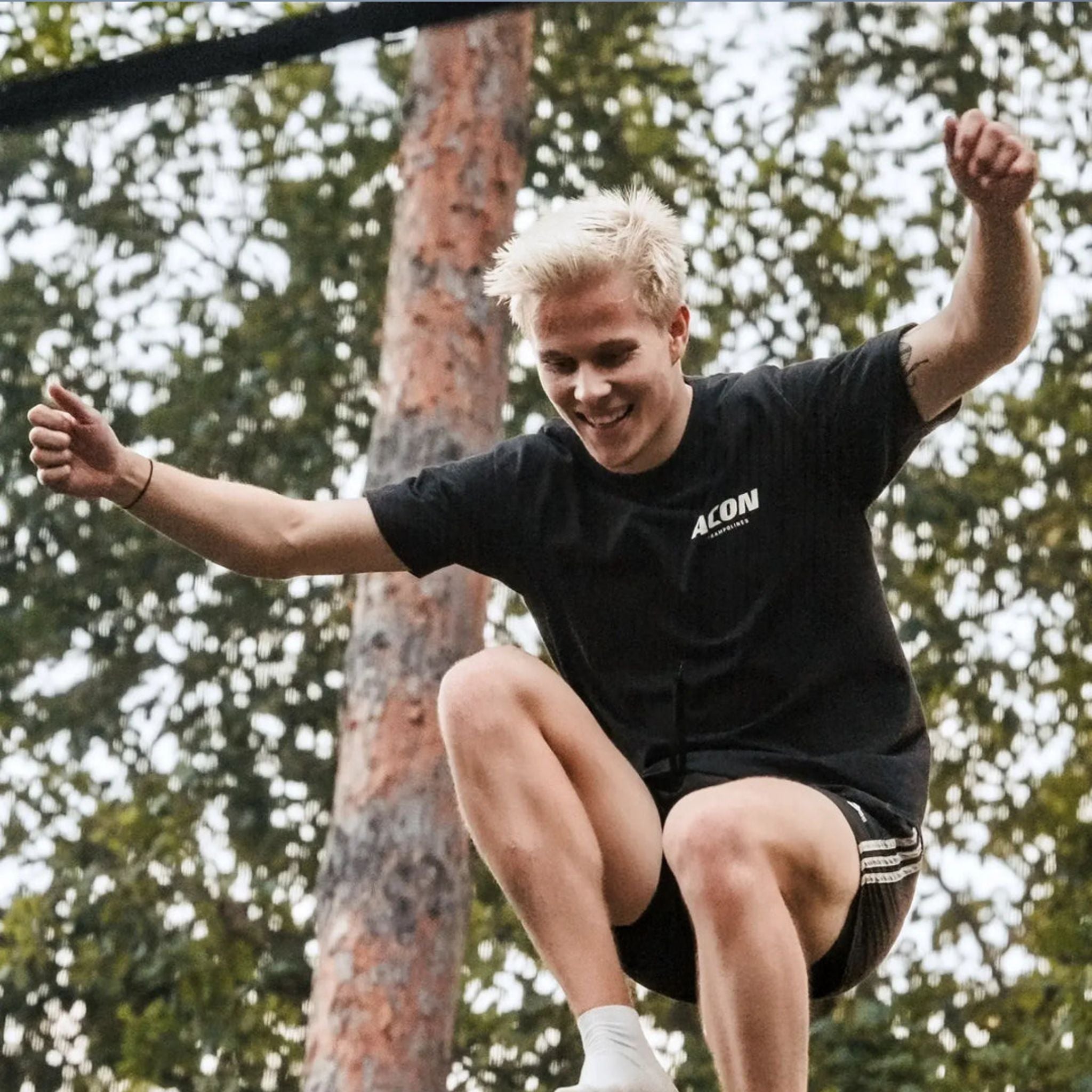 Mann springt auf Trampolin mit schwarzem T-Shirt