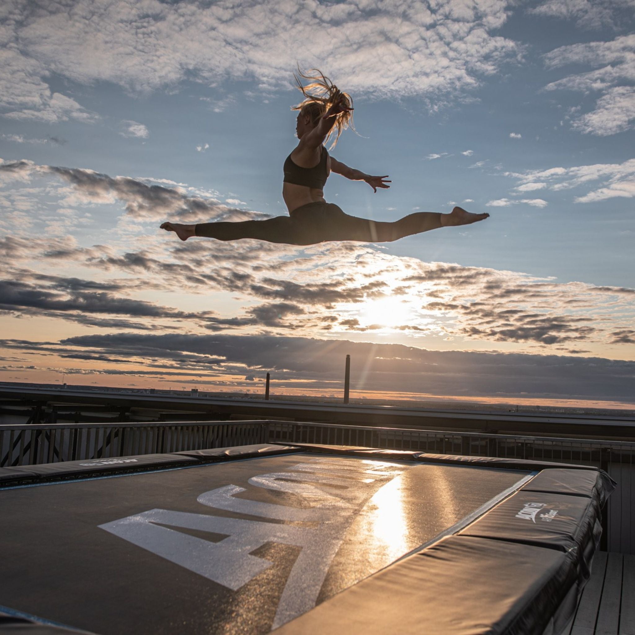 Frau springt auf einem Trampolin. Wie kann ich ein Trampolin im Boden verankern?