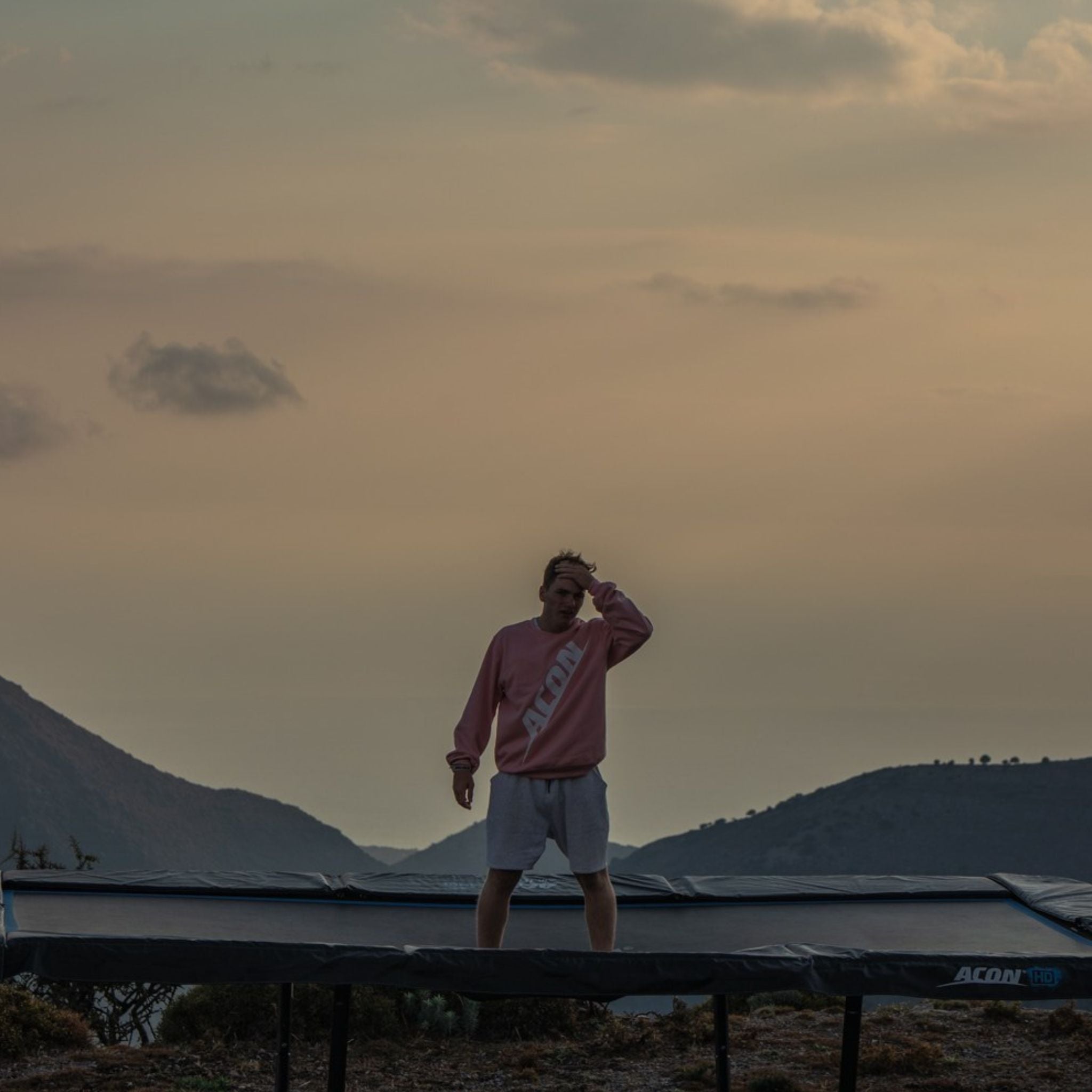 Mann steht auf einem Trampolin im Sonnenuntergang