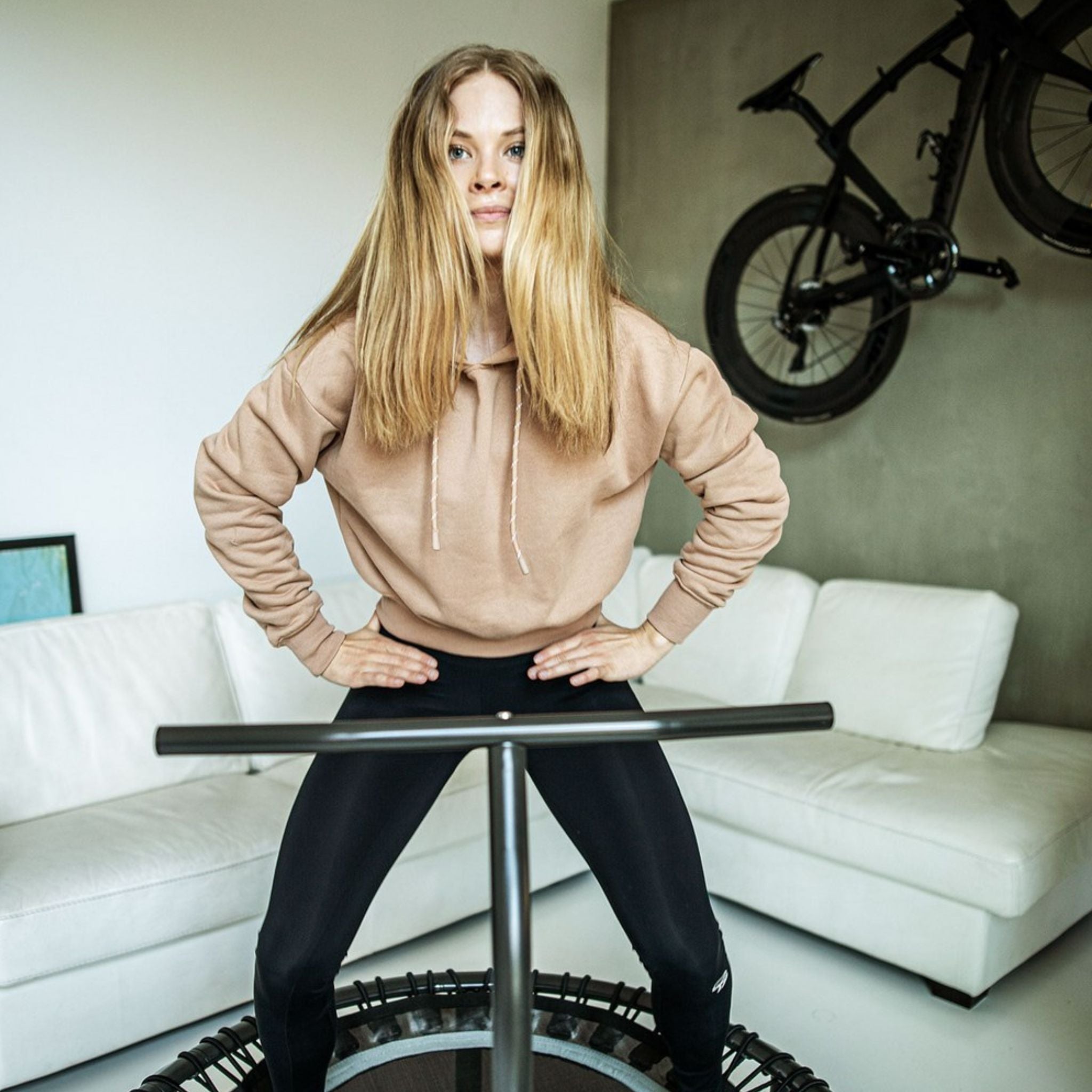 Frau trainiert auf einem Trampolin in ihrer Wohnung