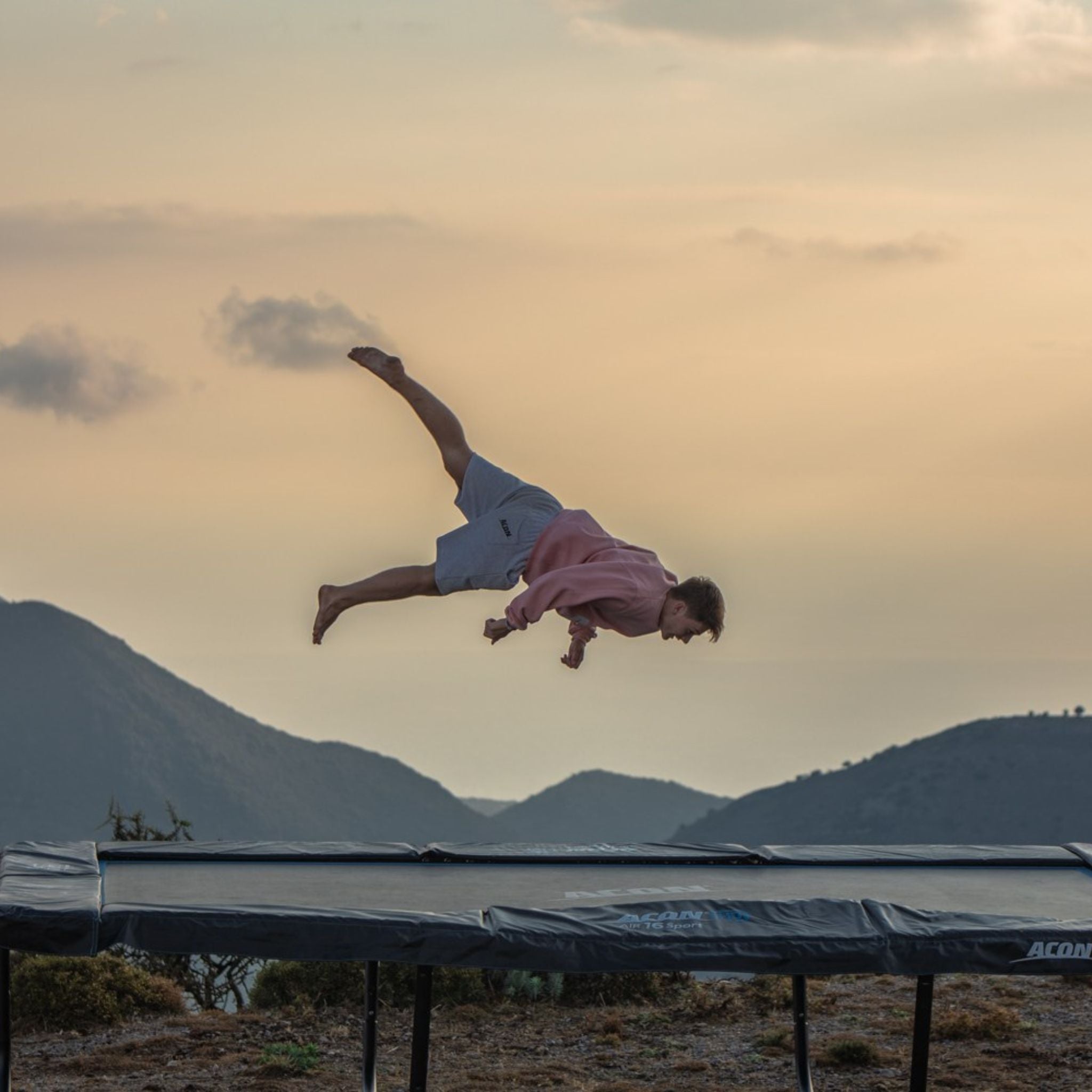 Mann springt auf Riesen Trampolin vor einer Berglandschaft