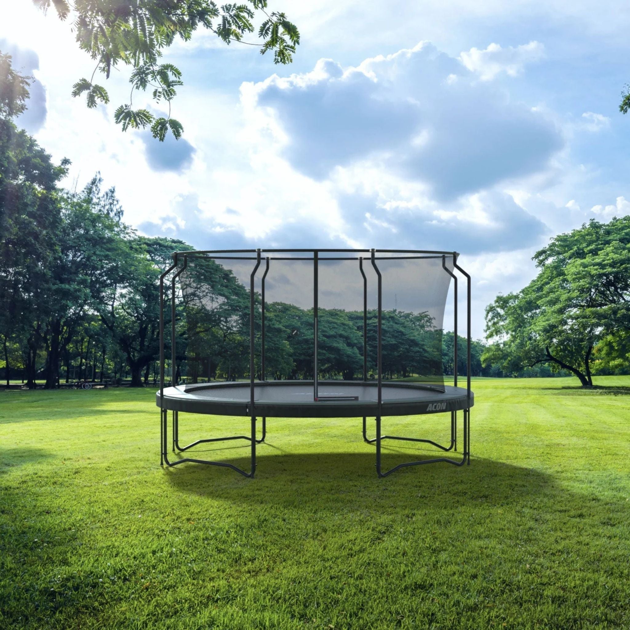 Ein Trampolin steht in einem grünen Feld, umgeben von Bäumen.