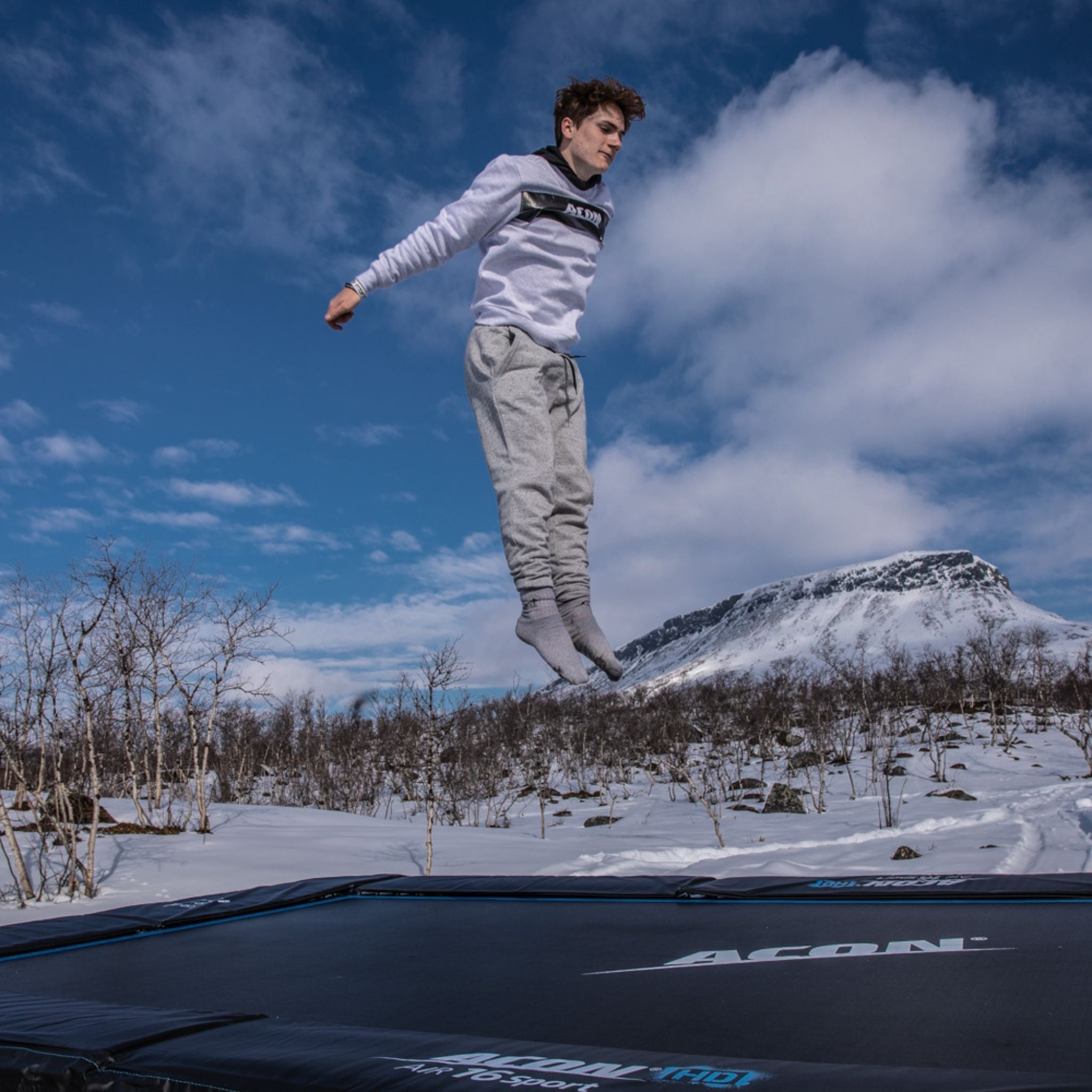 Ein Mann springt im Schnee auf einem Trampolin, um seine Trampolin skills zu verbessern.