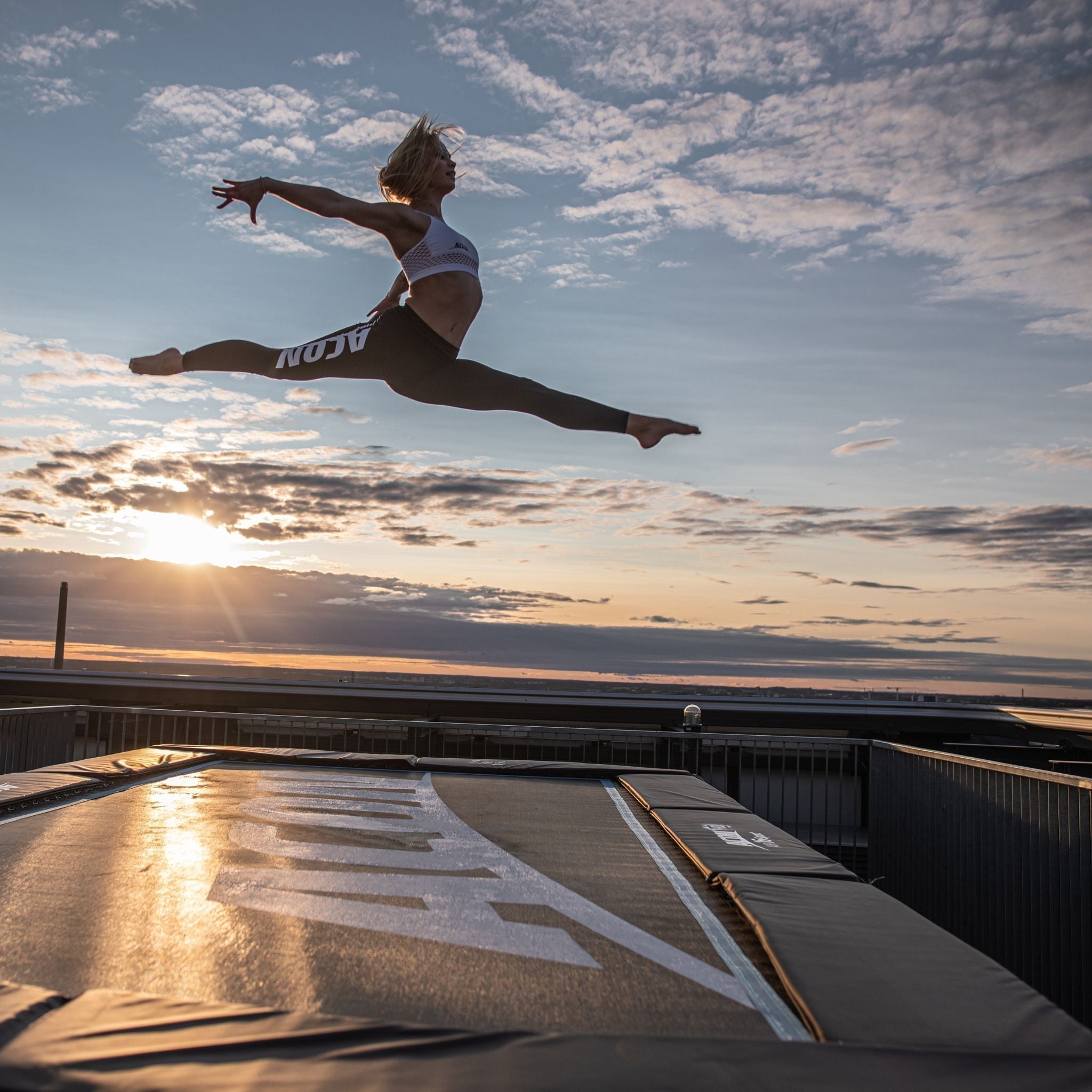 Eine Frau springt auf einem Trampolin bei Sonnenuntergang.