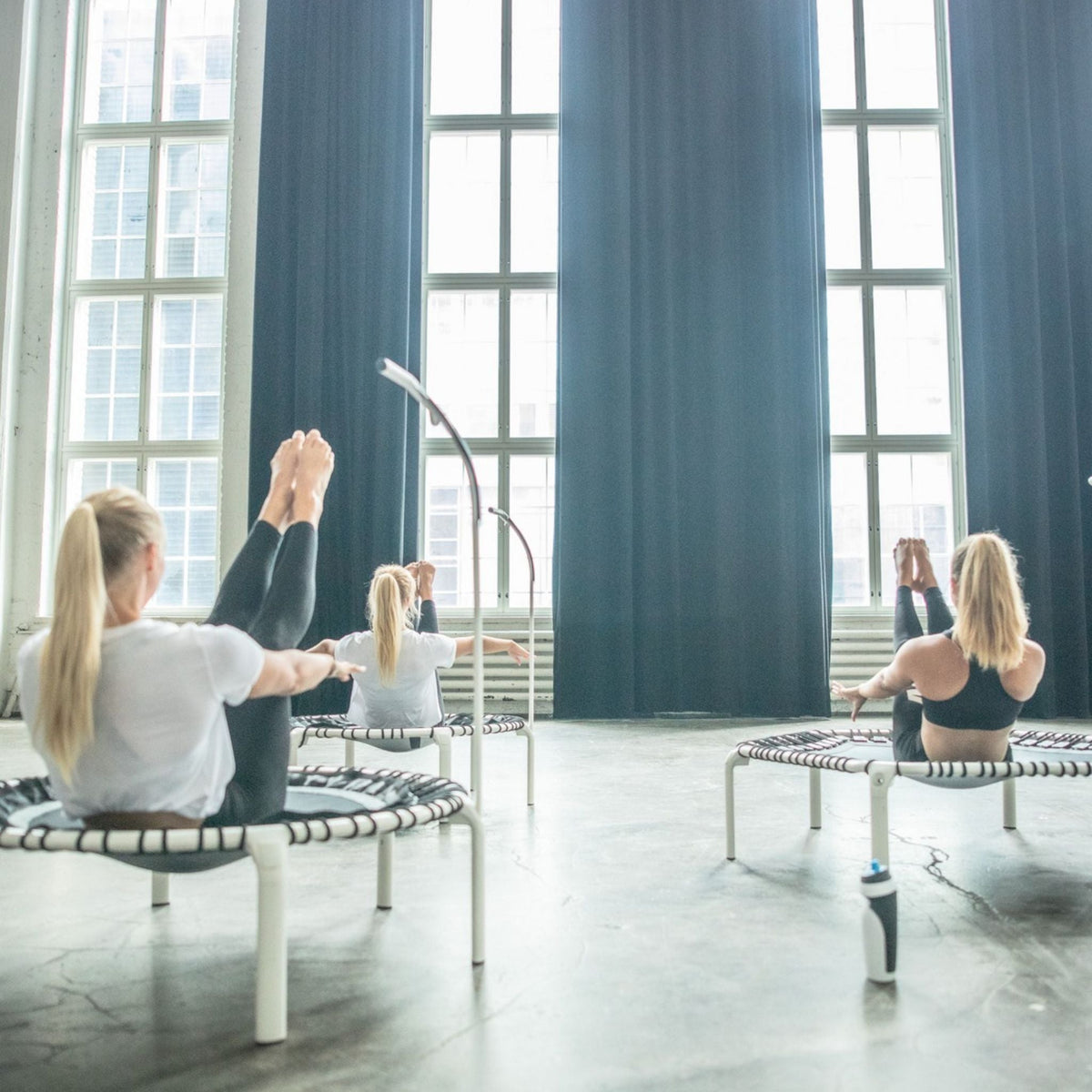 Eine Gruppe von Frauen trainiert in Intervallen auf Trampolinen