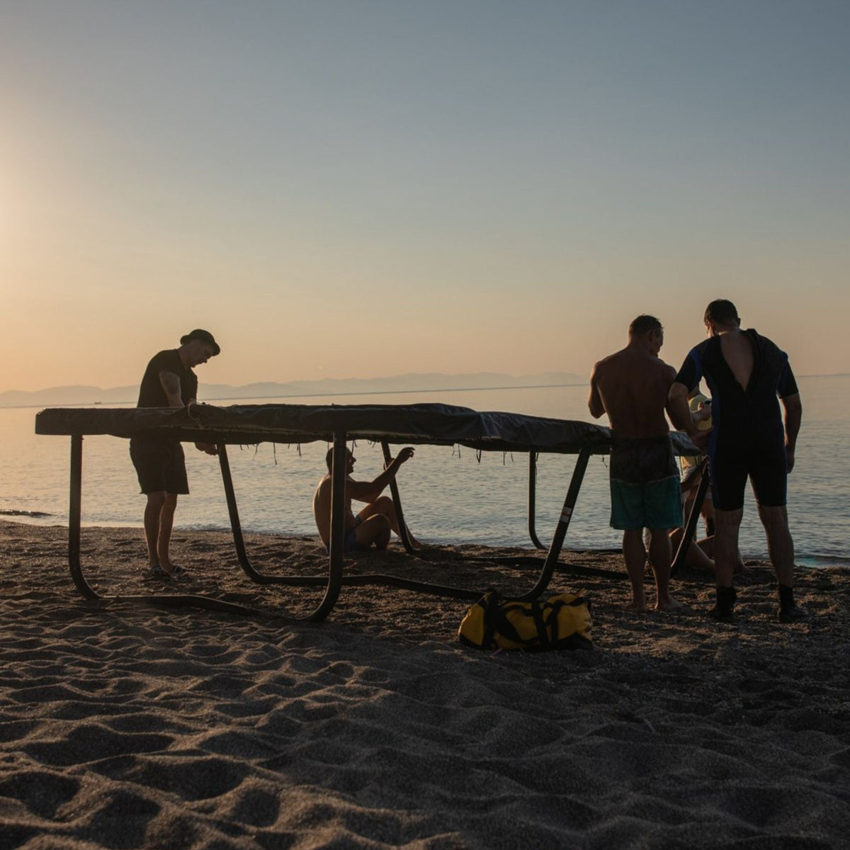 Leute am Strand mit Trampolin. Spikeball.