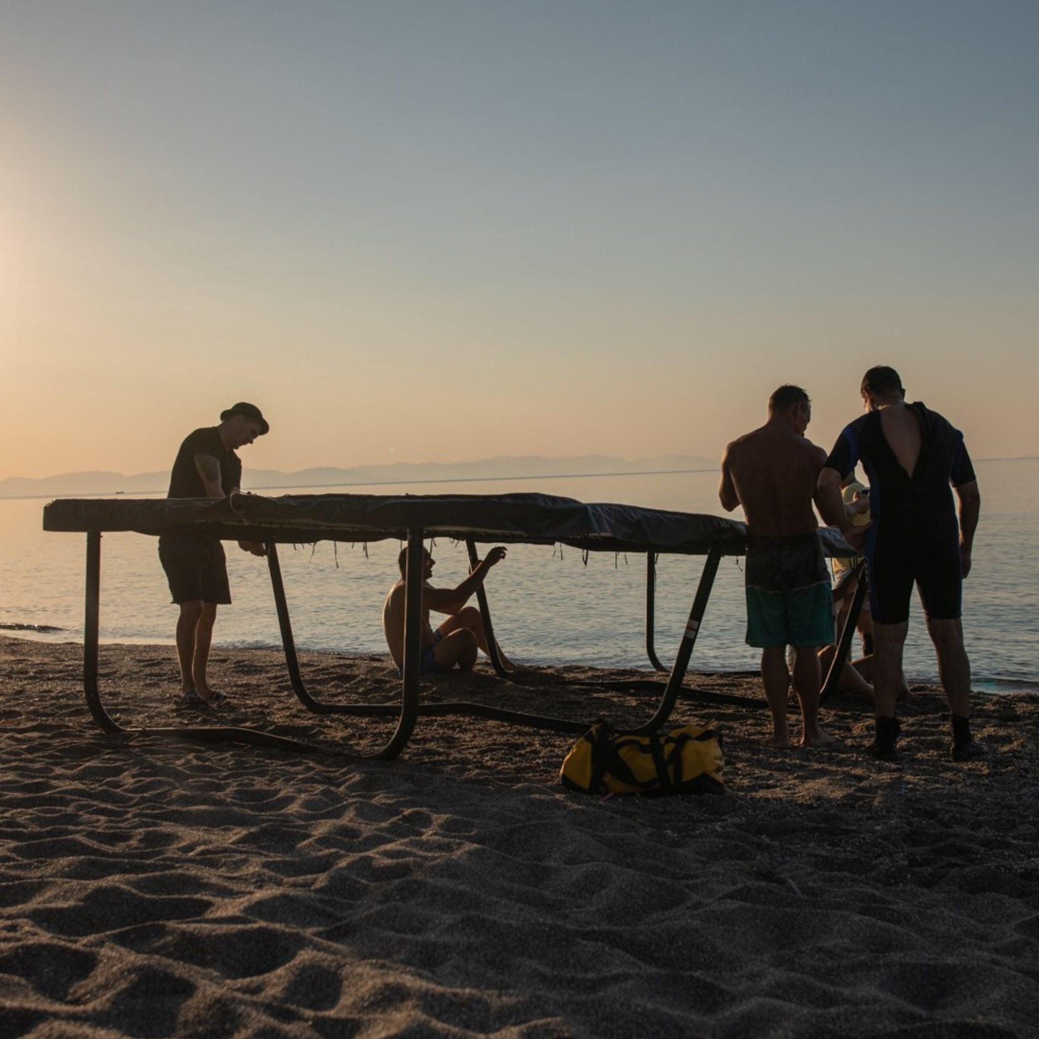 Leute am Strand mit Trampolin. Spikeball.