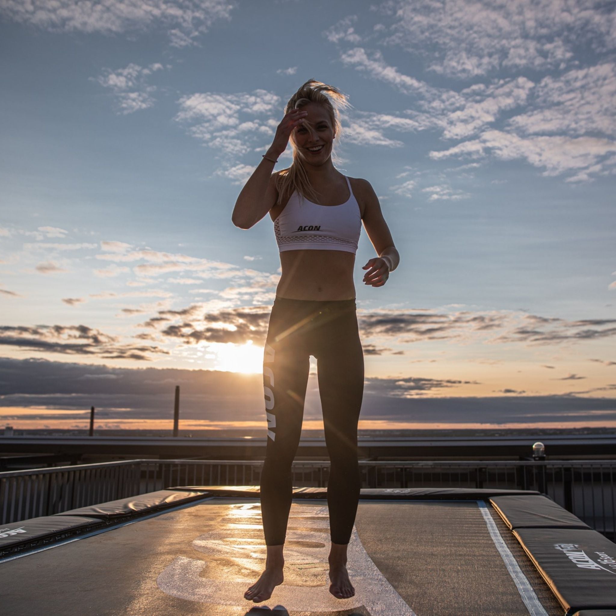 Frau steht auf einem ACON Sport Trampolin im Sonnenuntergang