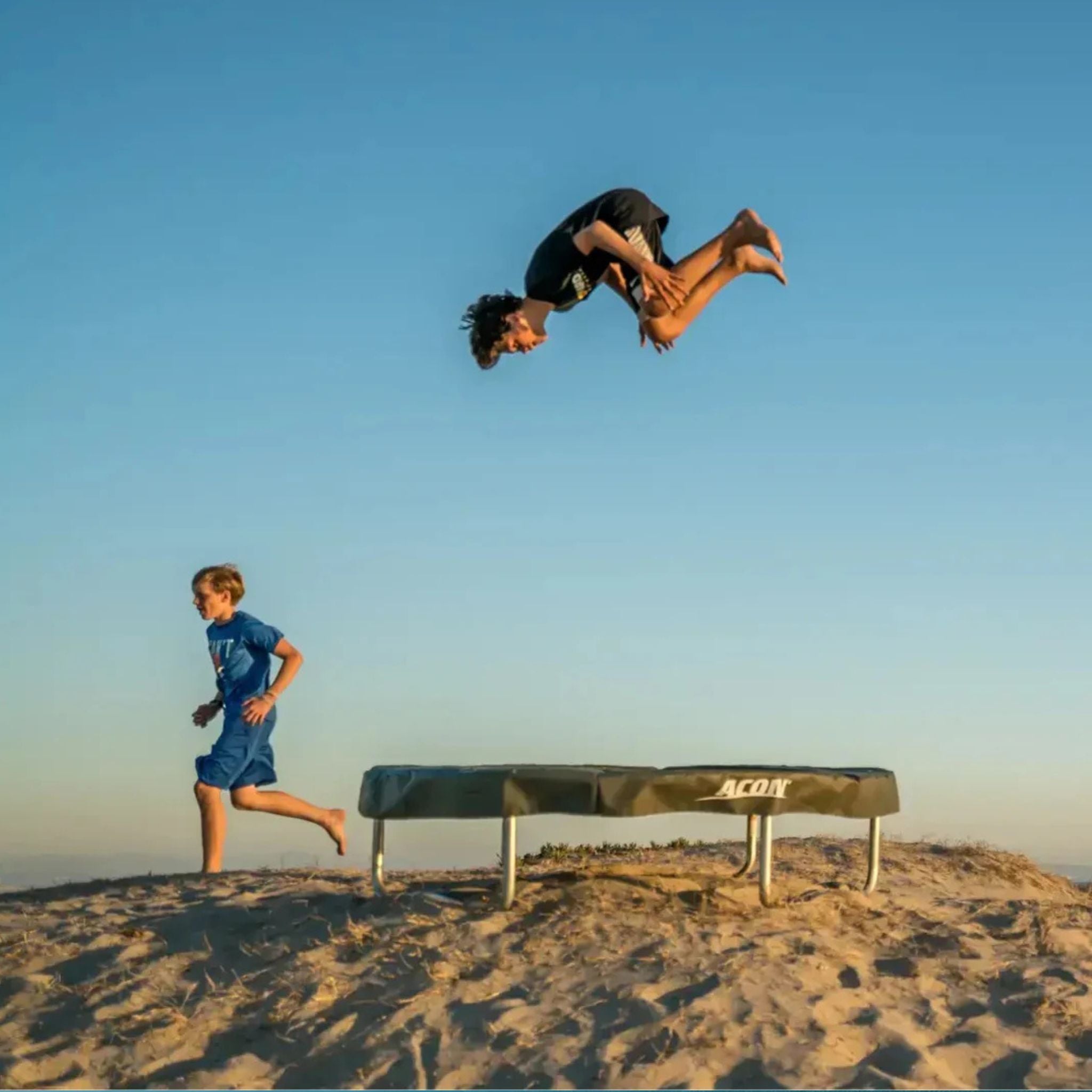 Zwei Kinder hüpfen auf einem Trampolin in der Sanddüne 