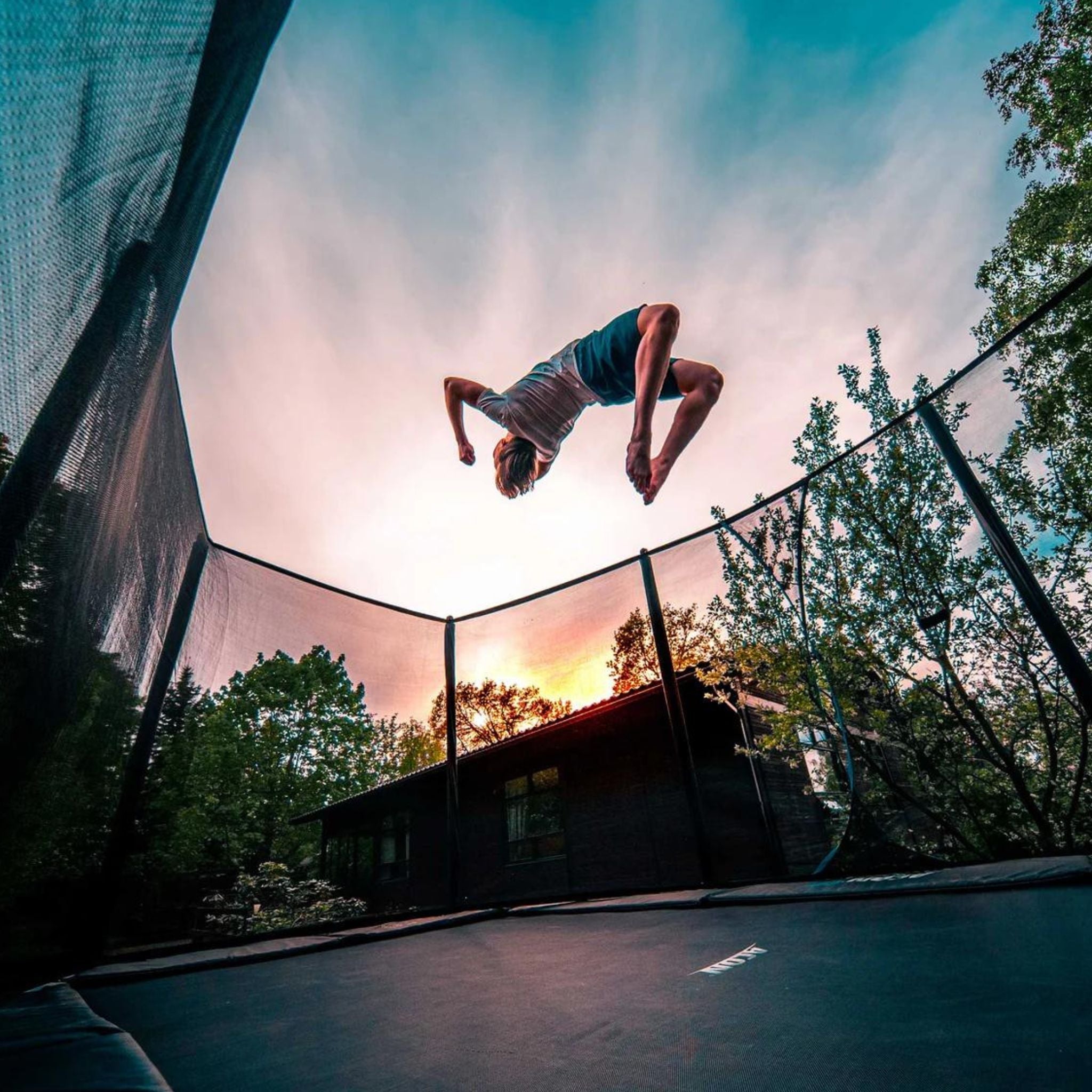 Junge macht Rückwärtssalto. Trampolin im Garten verboten