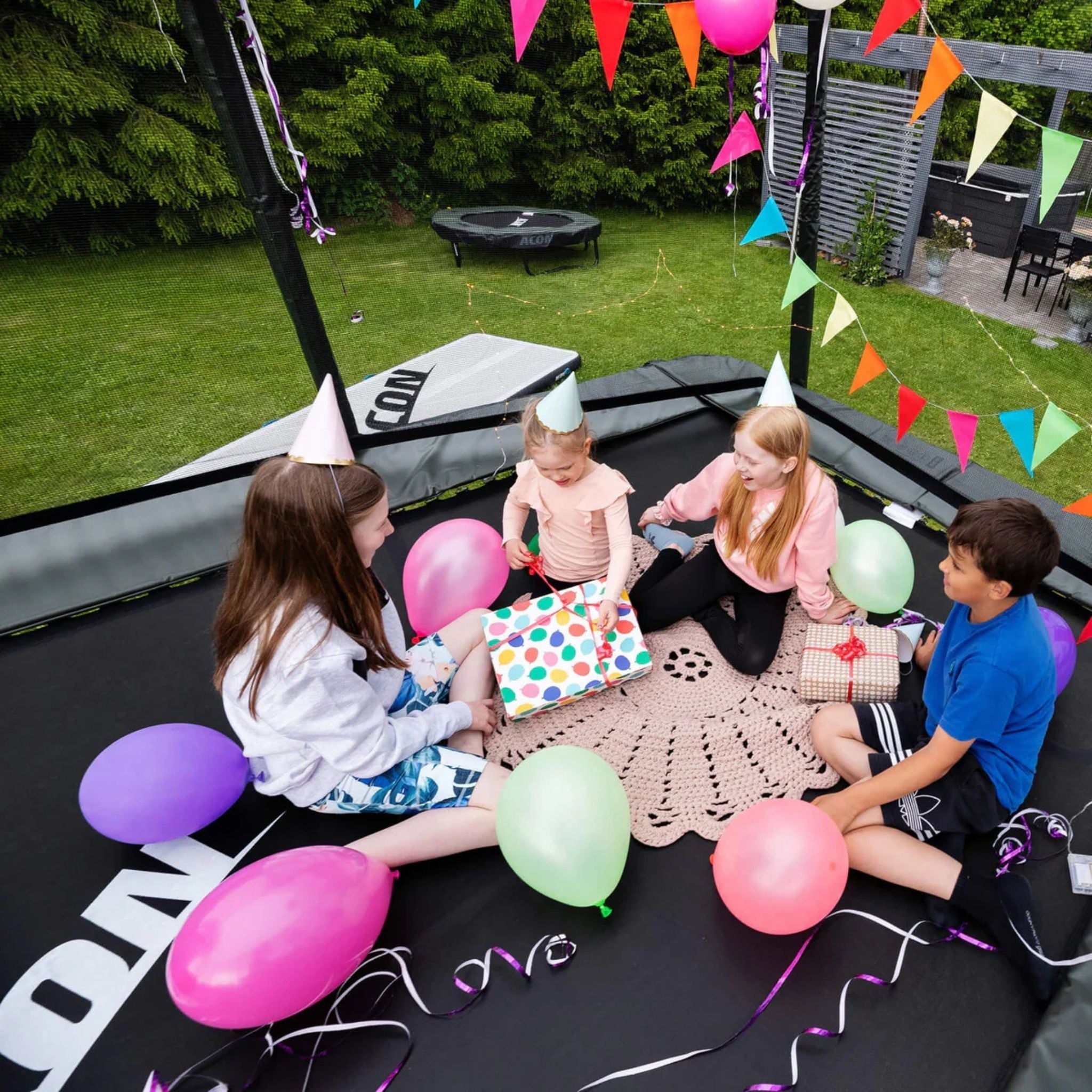 Kinder mit Geburtstagshüten auf einem ACON Trampolin im Freien