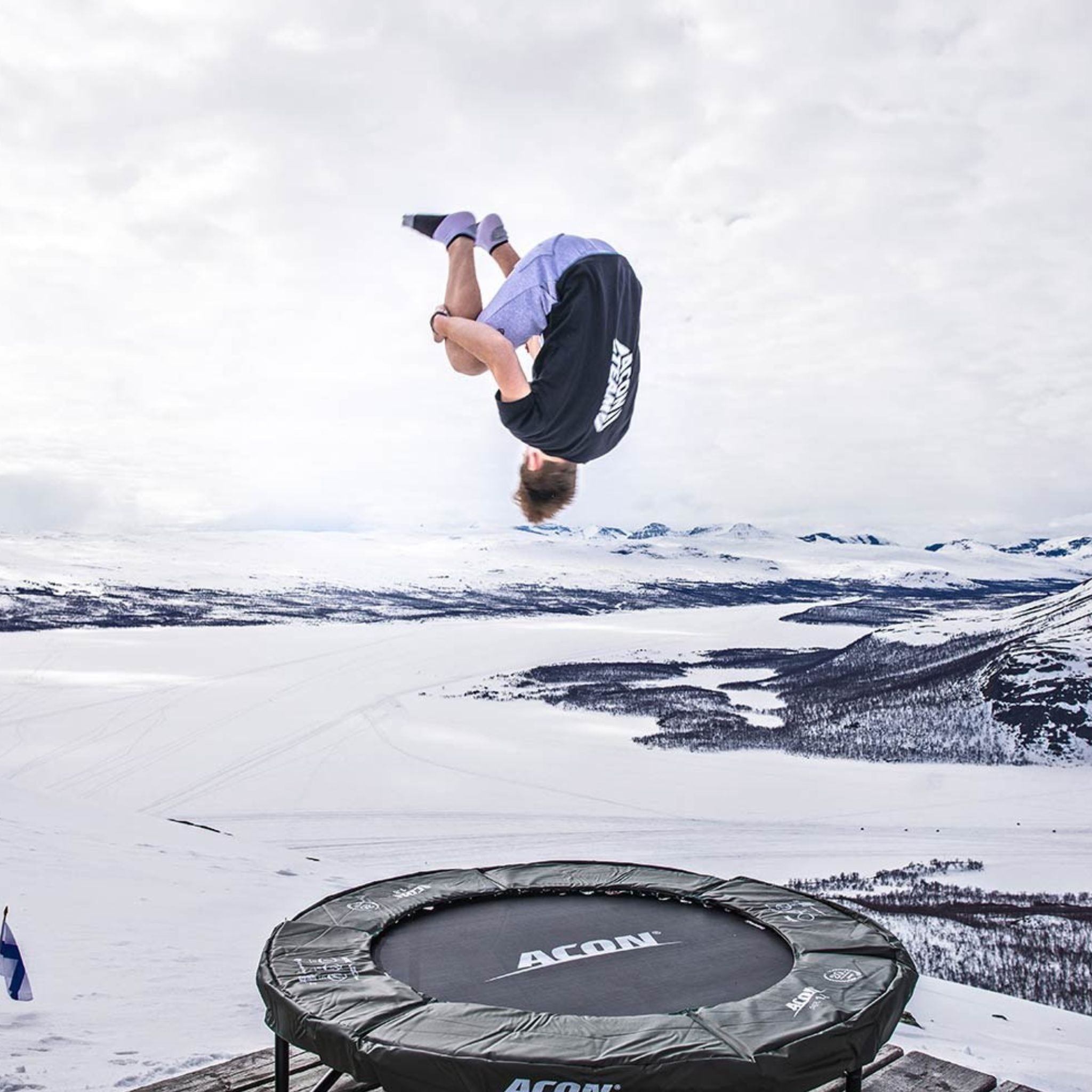 Mann macht einen Vorwärtssalto auf einem Trampolin im Schnee