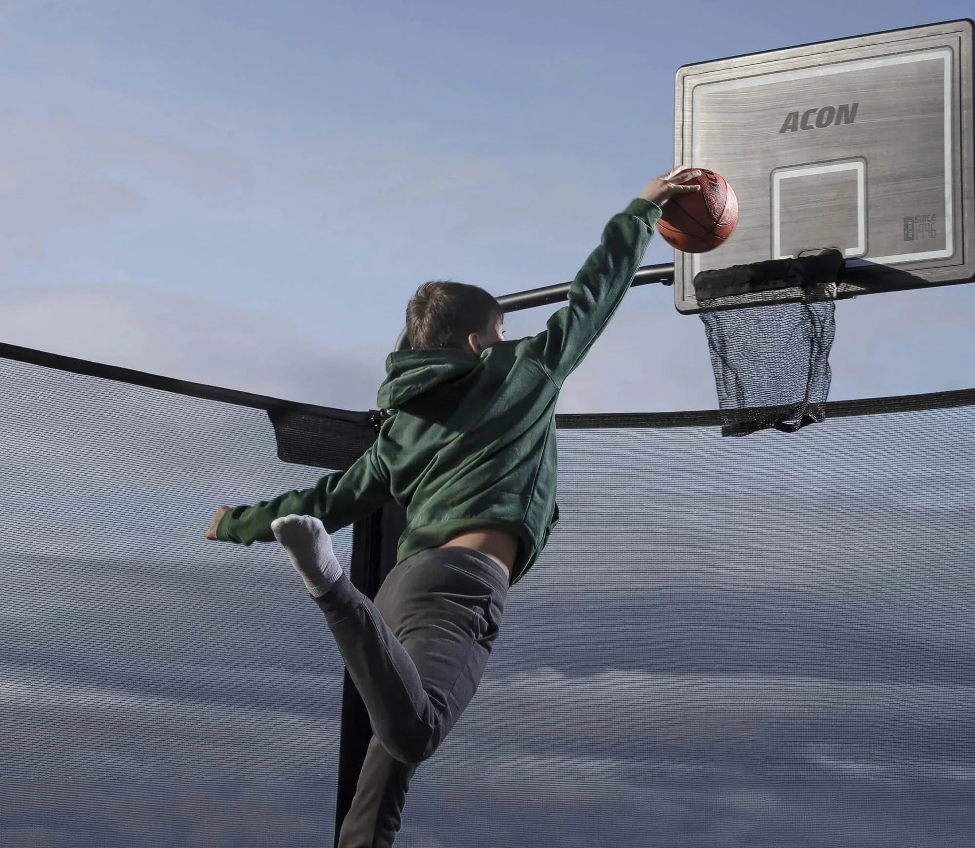 Der Junge wirft den Ball in den Trampolin-Basketballkorb.