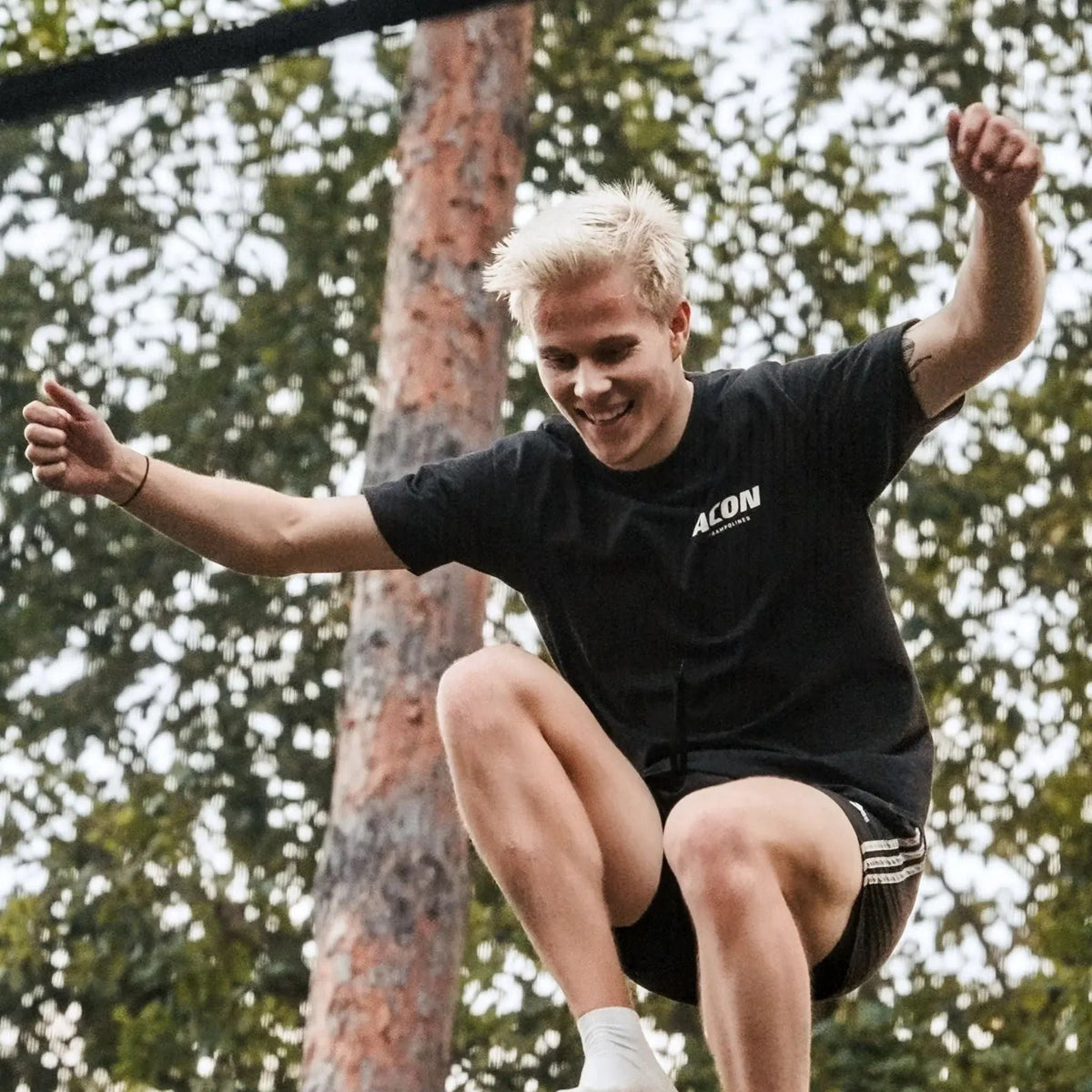 Mann mit hellen Haaren springt Trampolin in der Natur