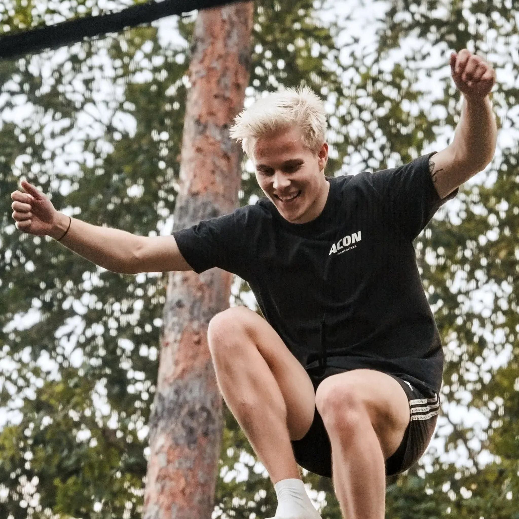 Mann mit hellen Haaren springt Trampolin in der Natur