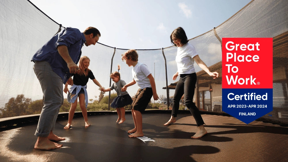 Familie auf einem Acon-Trampolin mit dem Zertifizierungssiegel „Great Place to Work“.
