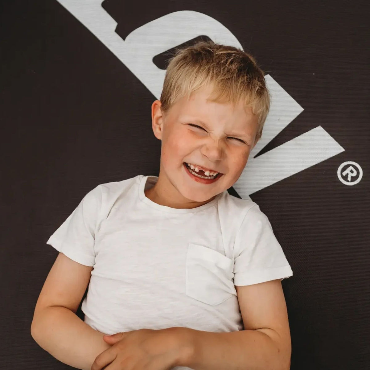Ein lächelnder Junge liegt auf der Sprungmatte eines Acon-Trampolins.