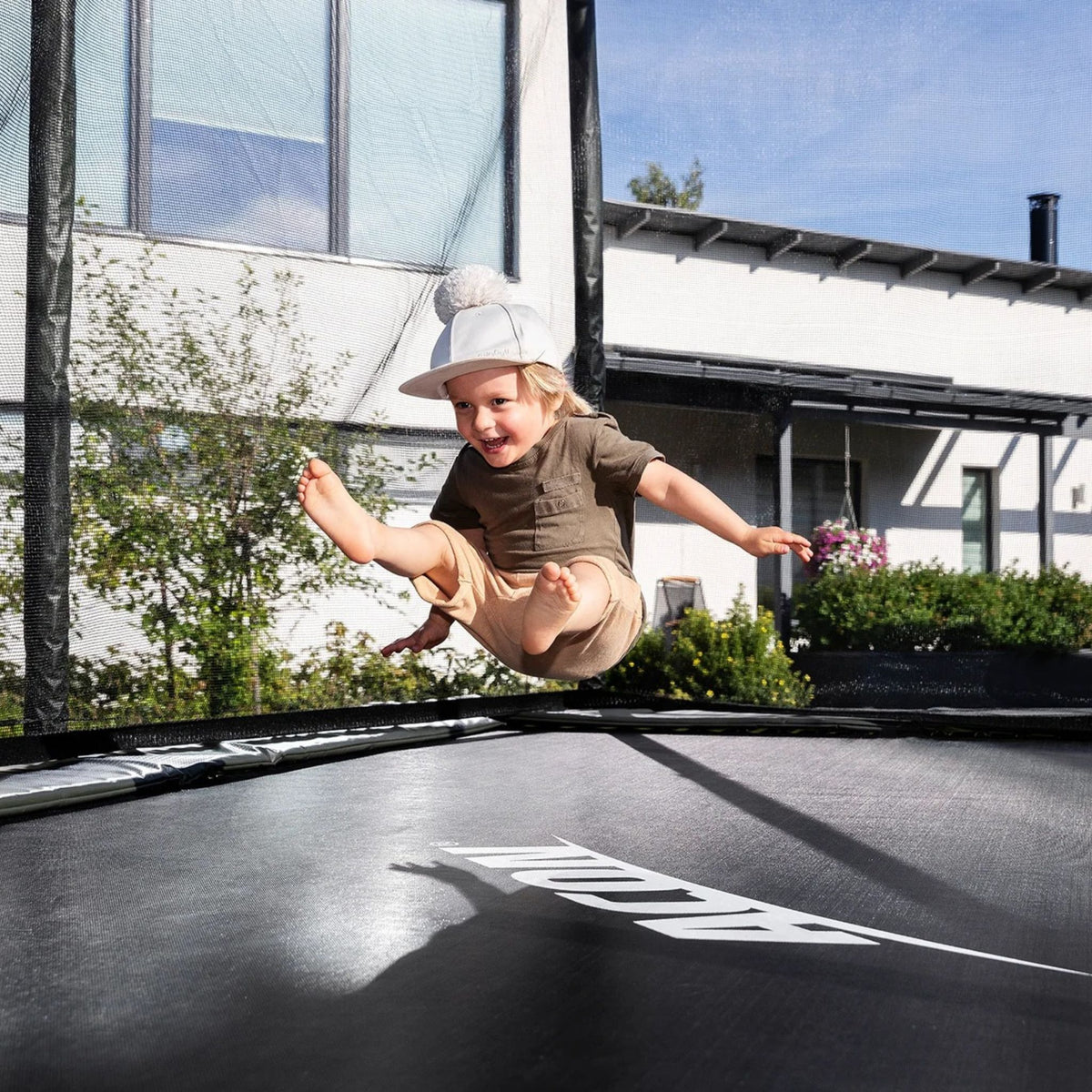 Ein Junge springt auf einem rechteckigen Acon-Trampolin mit Sicherheitsnetz.