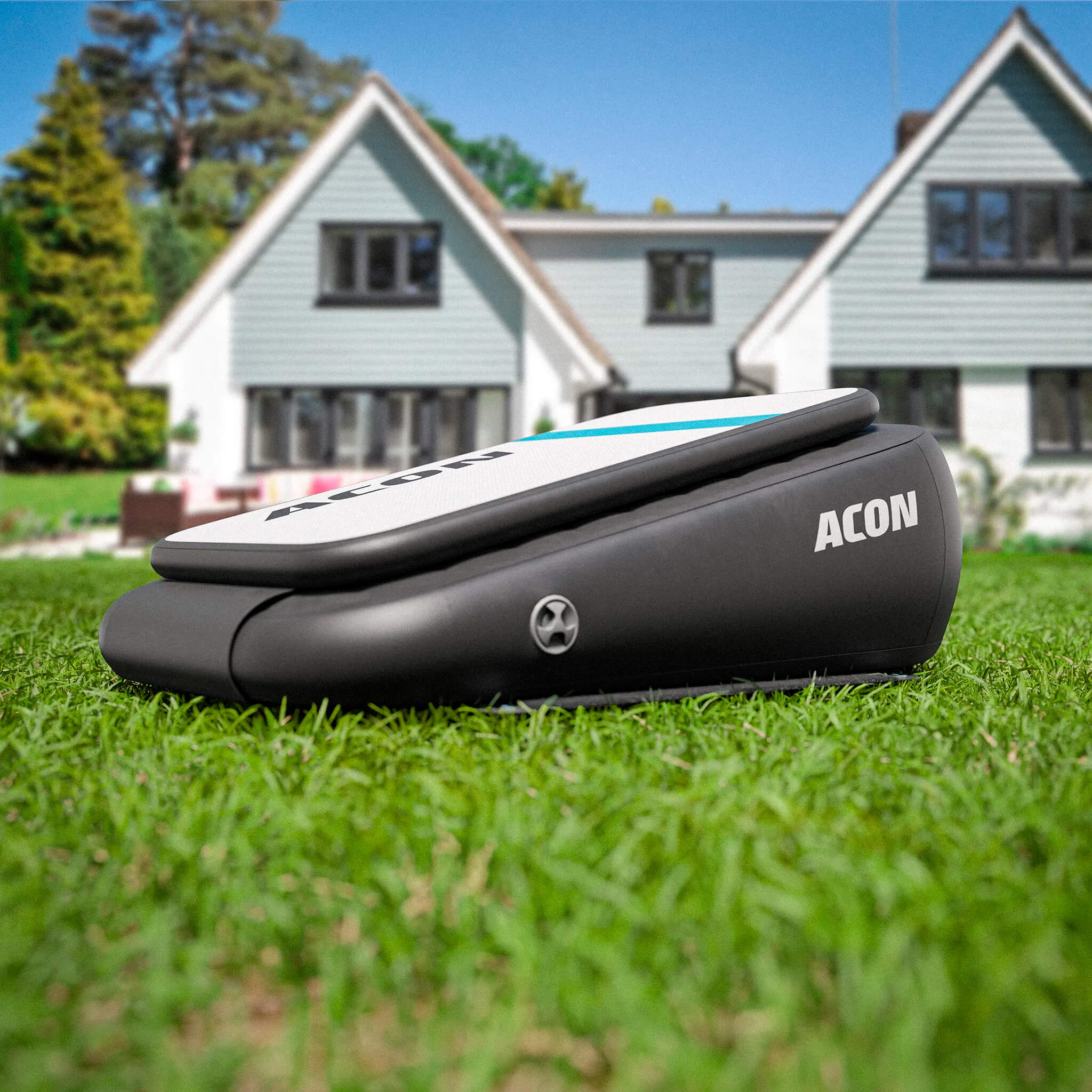 ACON Airboard auf einer Rasenfläche in einem sonnigen Garten, mit einem großen Haus im Hintergrund.