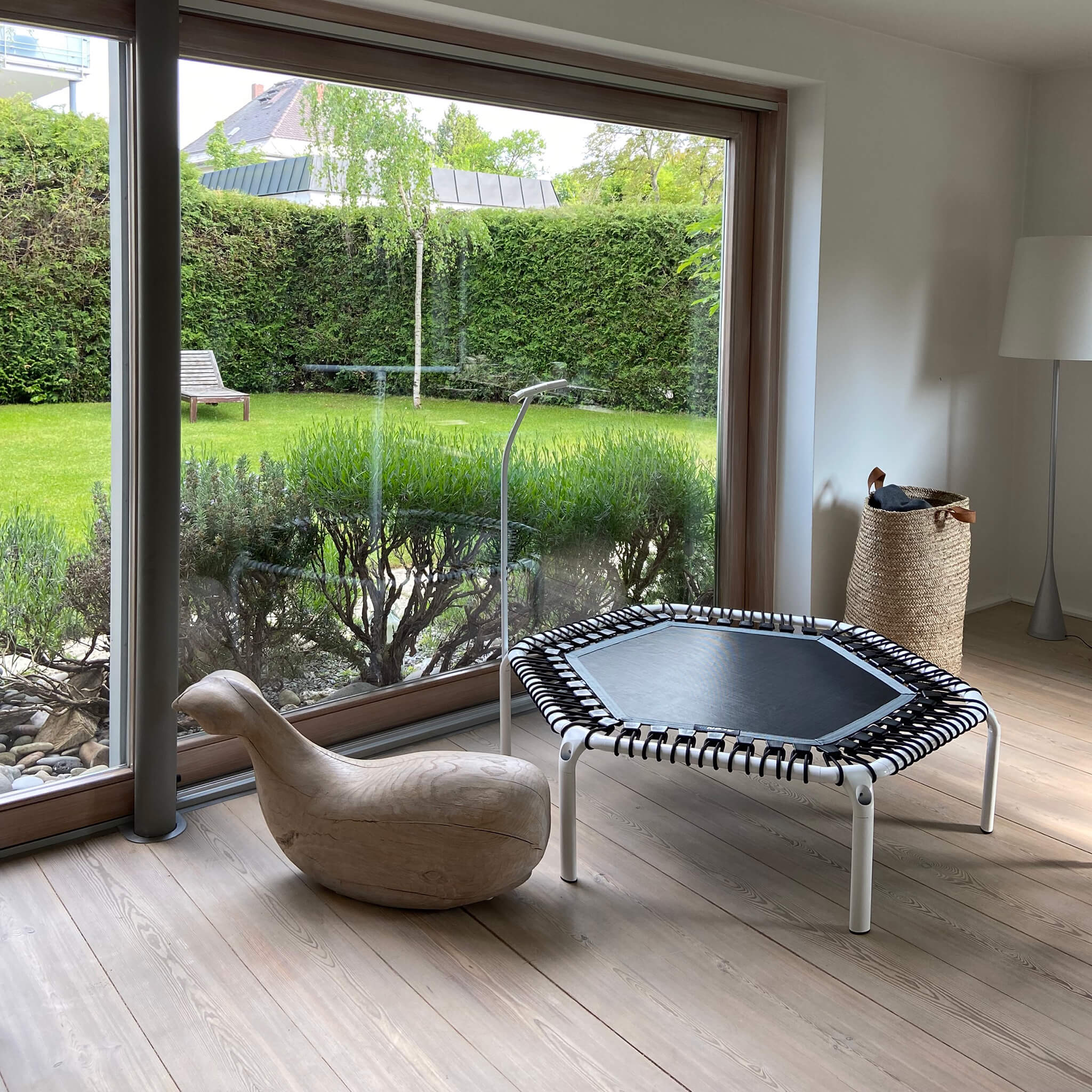 Weißer Acon Hexagonal Fitness-Trampolin im Wohnzimmer vor dem Panoramafenster.