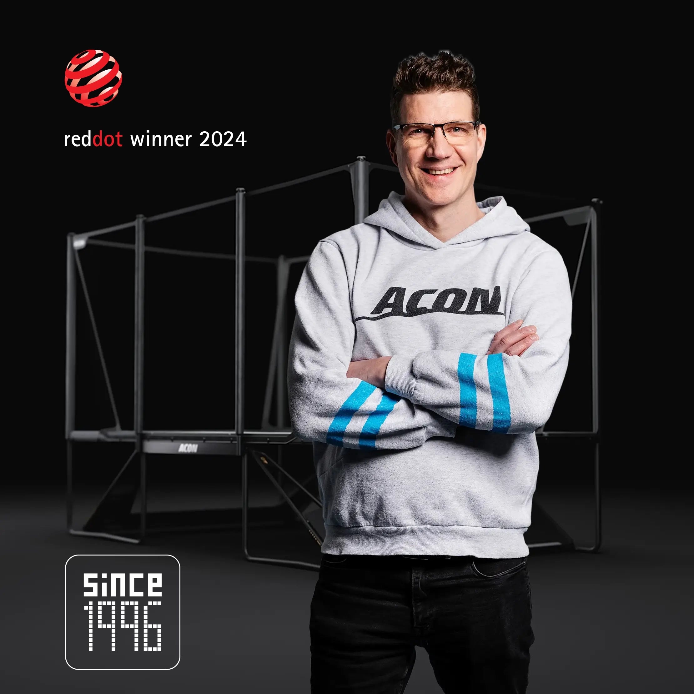 Acons Gründer Tarmo Sallinen steht vor einem X-Trampolin. Im Bild sind das Red Dot Awarded 2024‑Emblem und das Seit 1996‑Zeichen zu sehen.