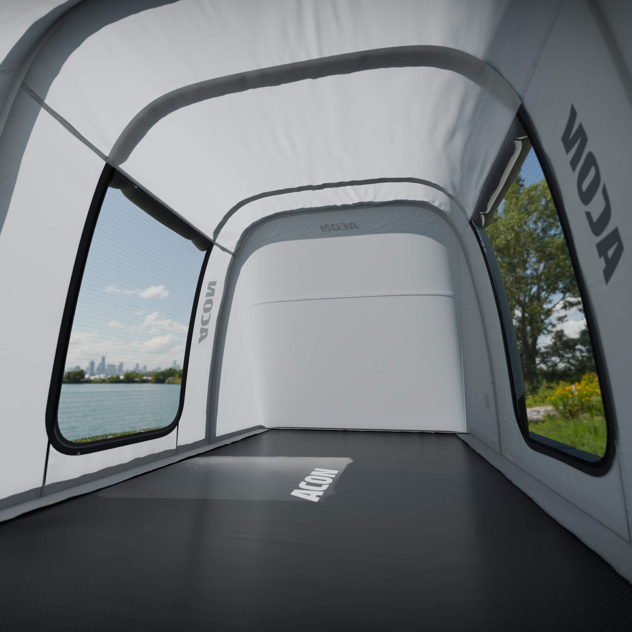 Innenansicht des ACON Trampolin-Zelts mit großen Mesh-Fenstern und Blick auf eine sonnige Parklandschaft.