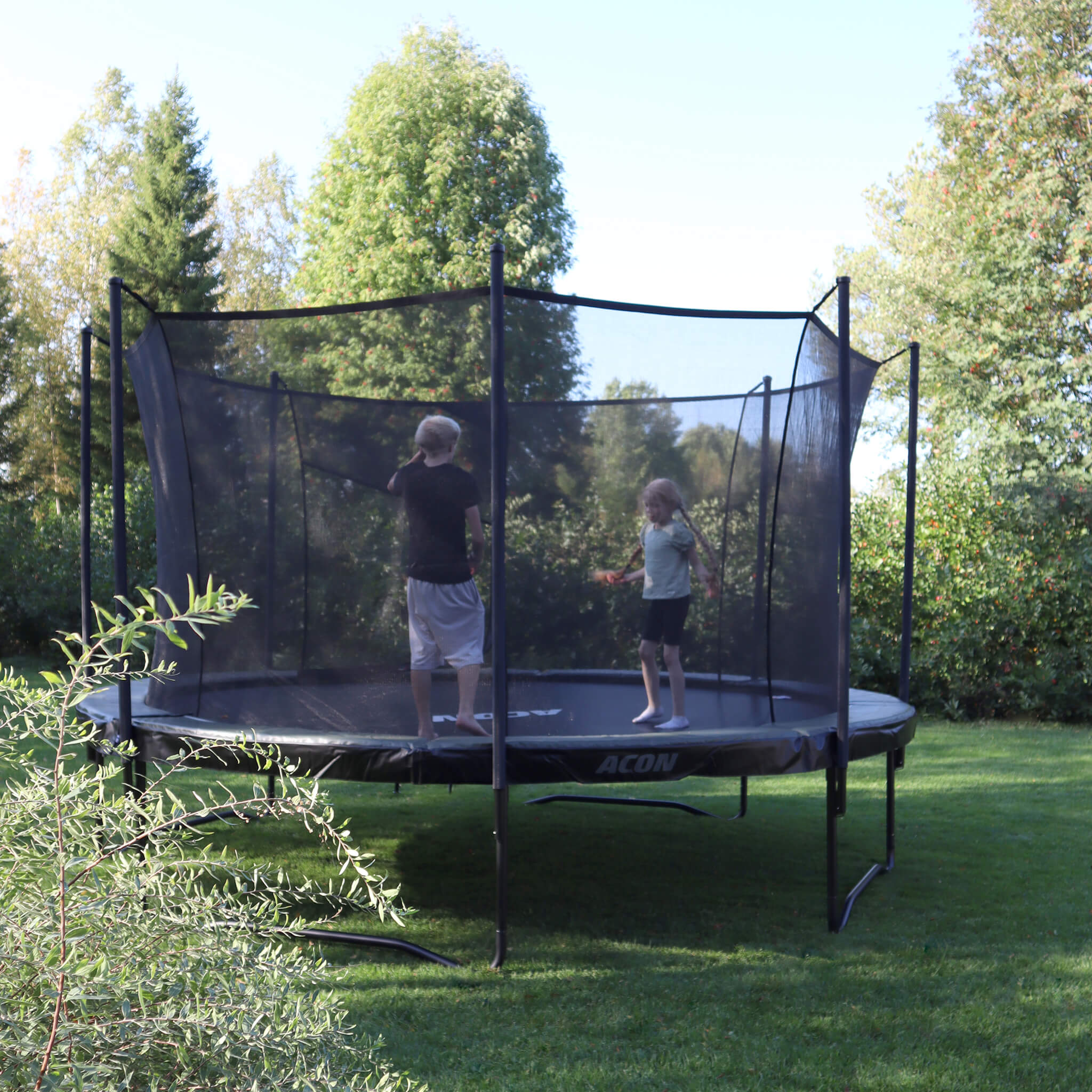 Acon Air-Trampolin im sommerlichen Garten. Zwei Kinder springen auf dem Trampolin.