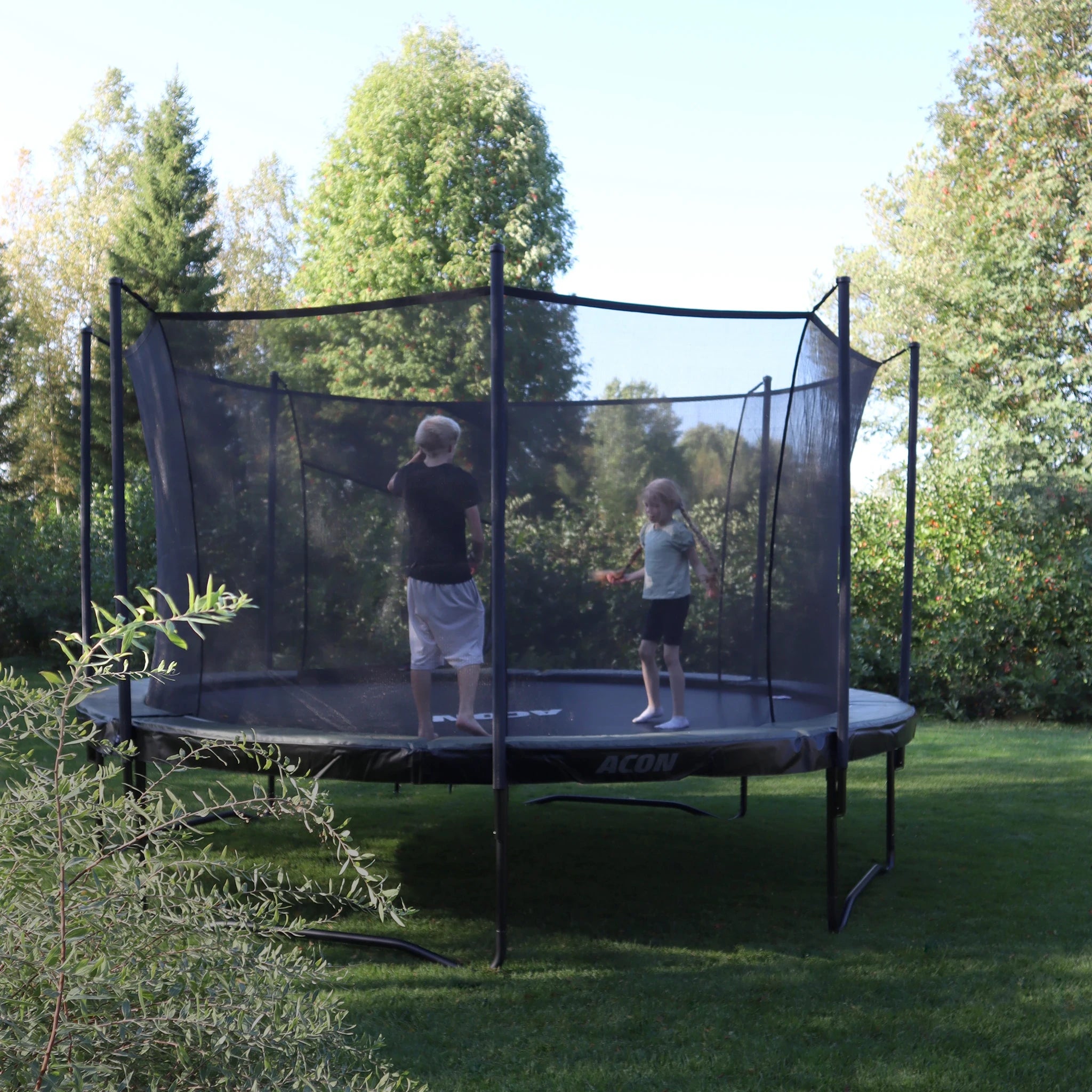 Acon Air-Trampolin im sommerlichen Garten. Zwei Kinder springen auf dem Trampolin.