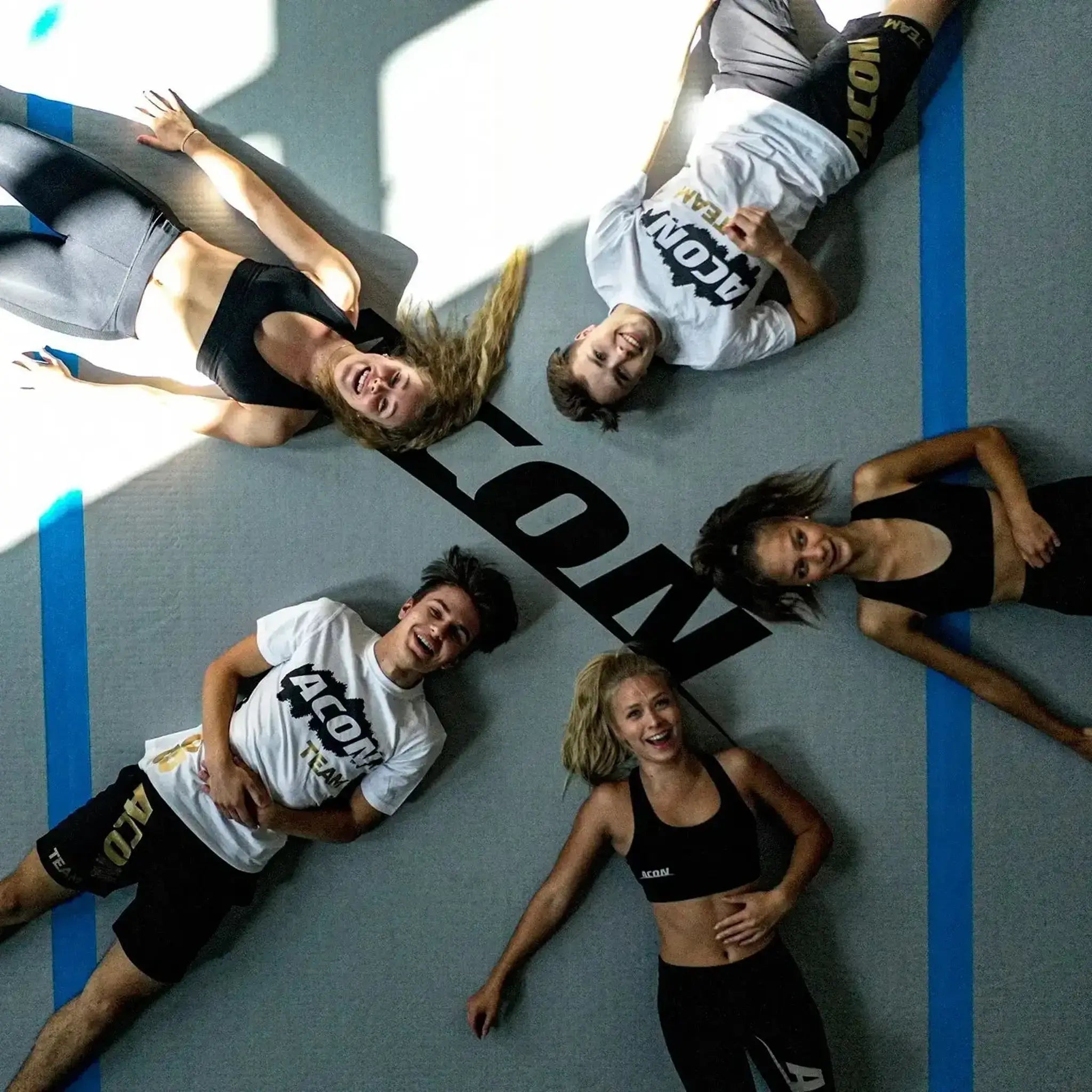 Fünf Menschen in athletischem Outfit liegen auf einem ACON Airtrack.
