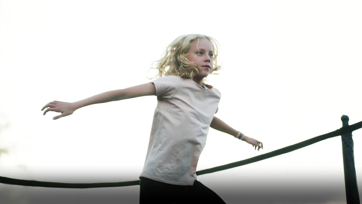 Mädchen, das mit konzentriertem Blick auf einem Acon-Trampolin hüpft.