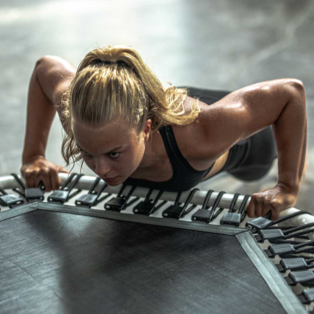 Frau beim Training auf dem Acon FIT 1,41m Hexagon Trampolin weiß.