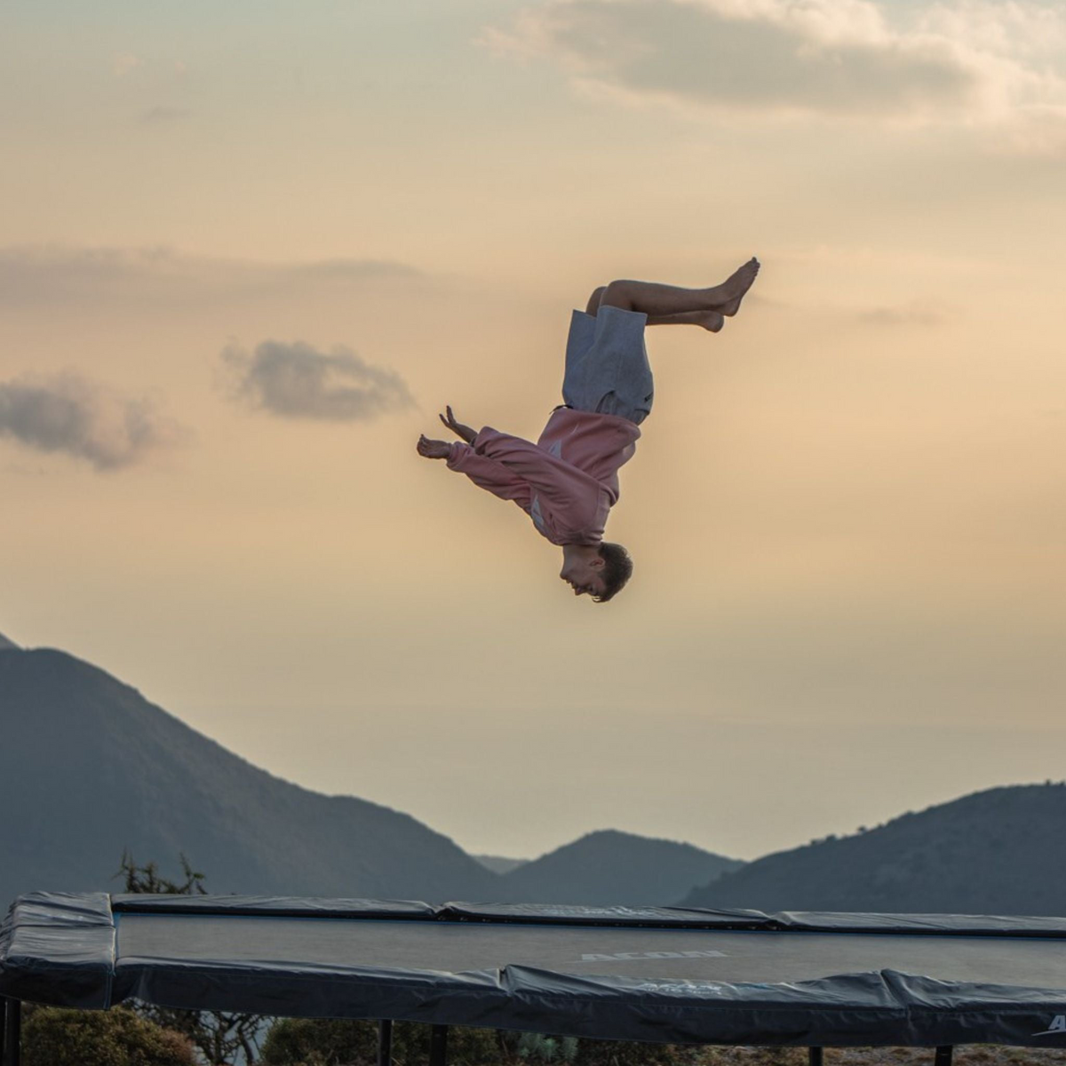 Mann macht Frontflip auf einem Trampolin im Freien