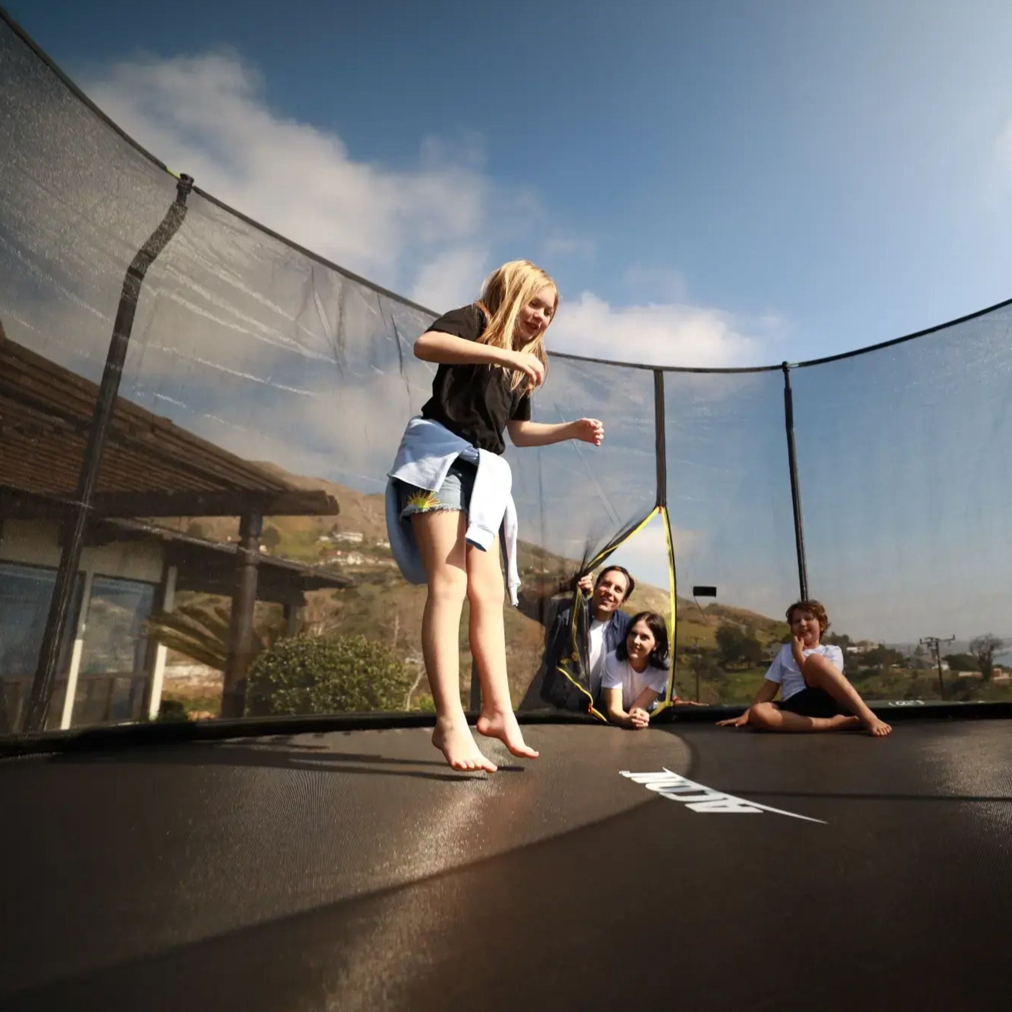 Familie hüpft auf Trampolin im Garten