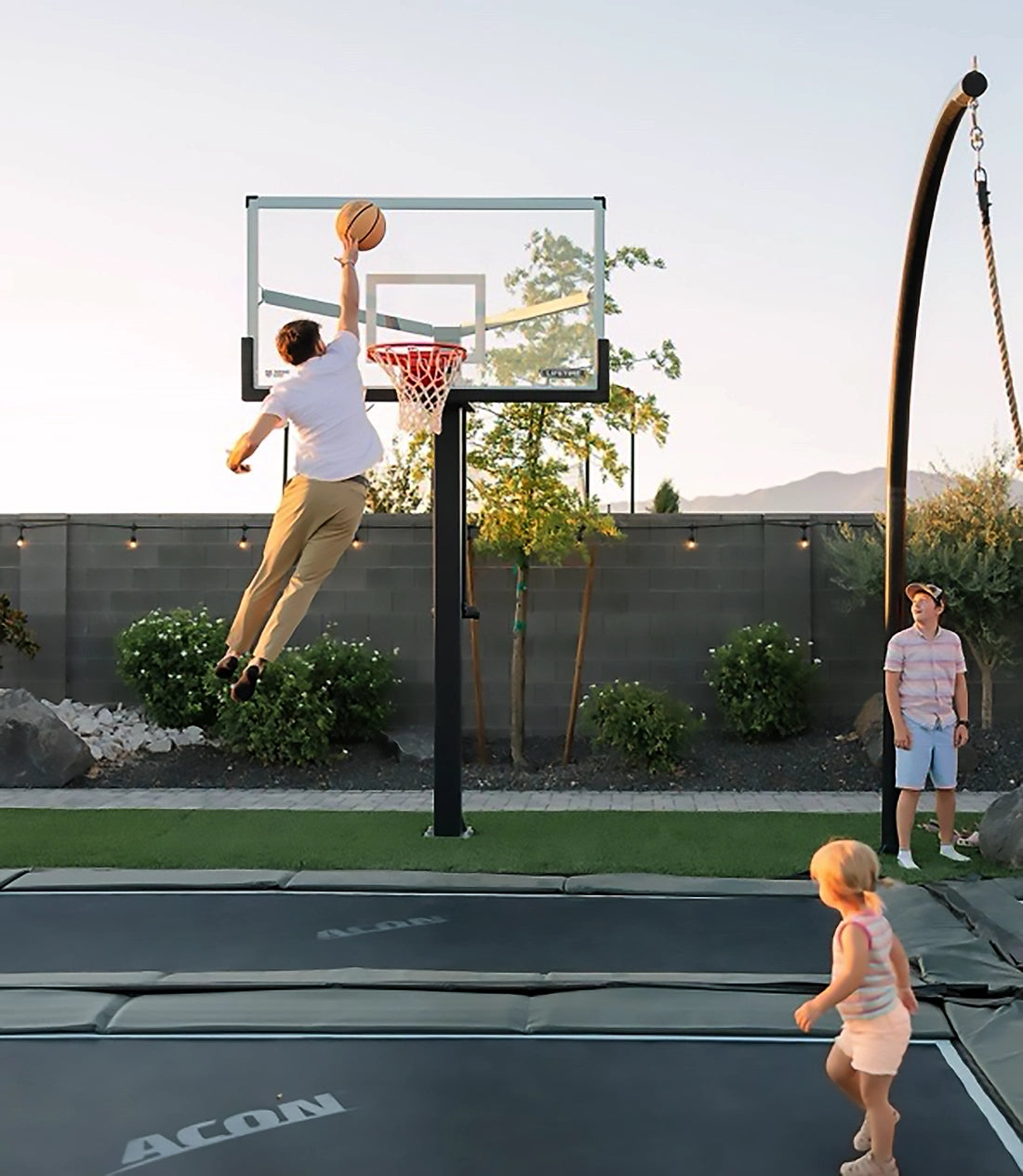 Ein Mann springt auf einem im Boden montierten Acon HD-Trampolin und wirft einen Basketball.