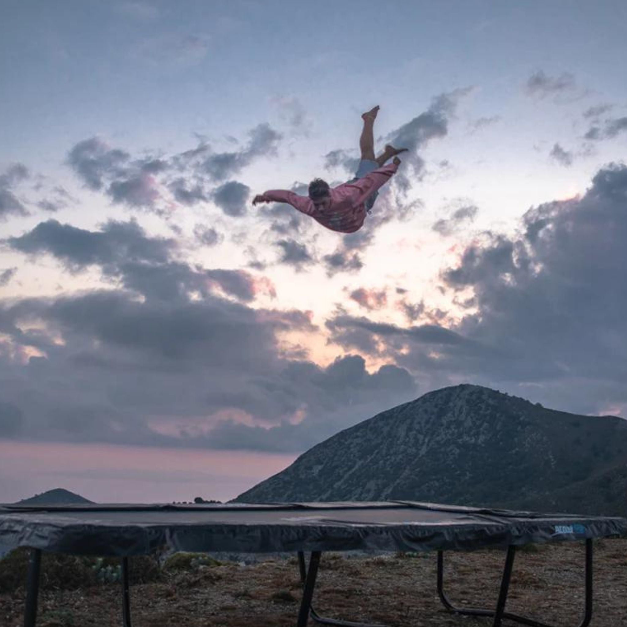 Mann hüpft Trampolin im Sonnenuntergang 