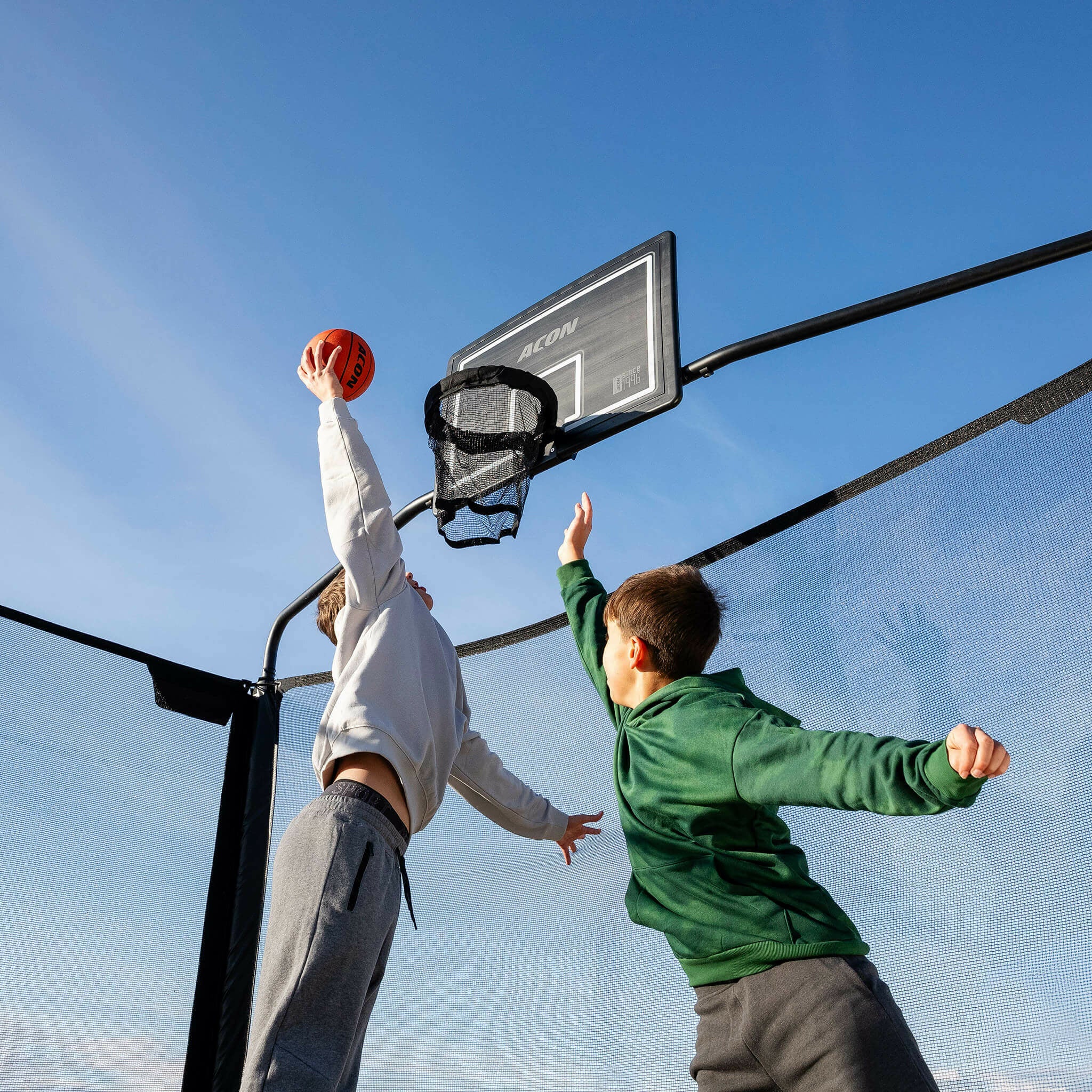 Zwei Jungen spielen Basketball auf dem Acon X Trampolin.