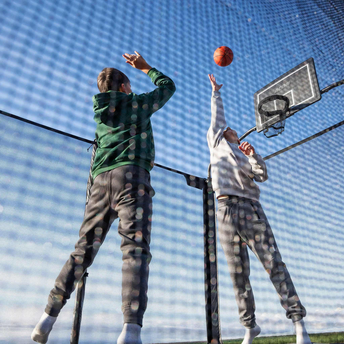 Zwei Jungen spielen Basketball auf dem Acon X Trampolin.