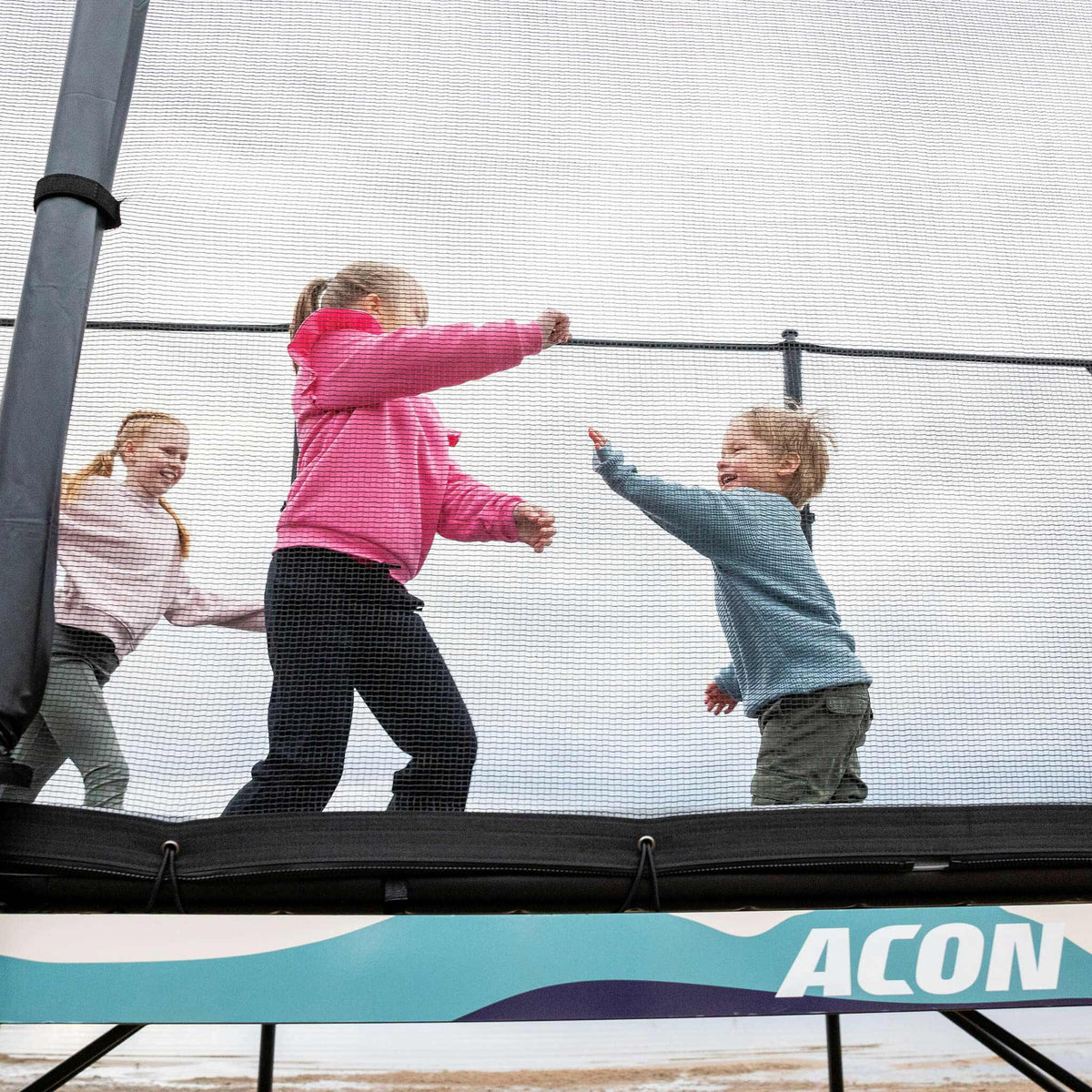 Drei Kinder spielen auf dem Acon X Trampolin.