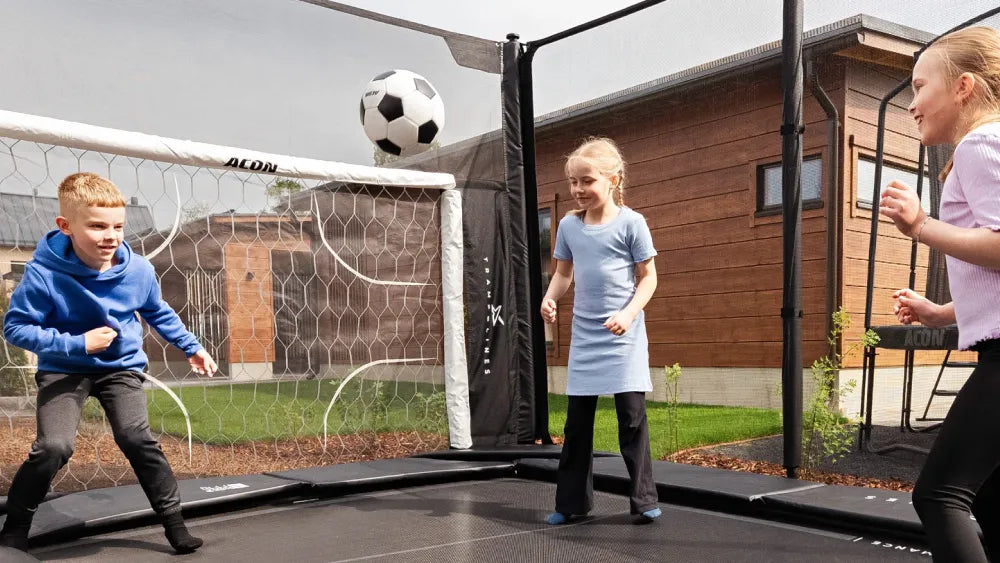 Kinder spielen Fußball auf einem Acon X Trampolin mit ACON Soccer Goal.