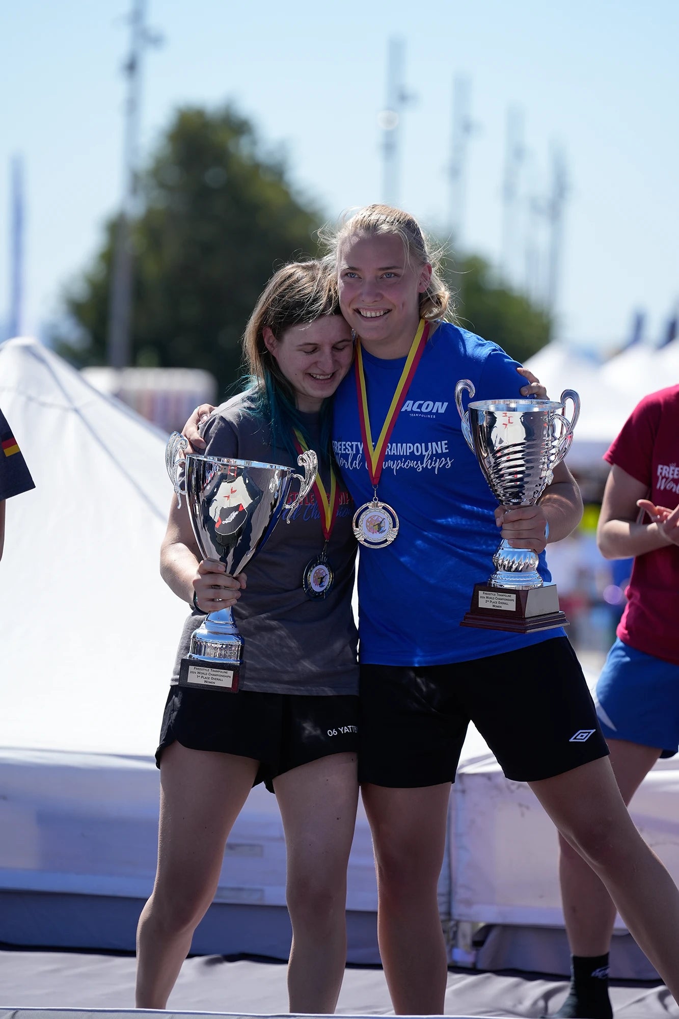 Sieger eines Trampolinwettbewerbs umarmen sich.