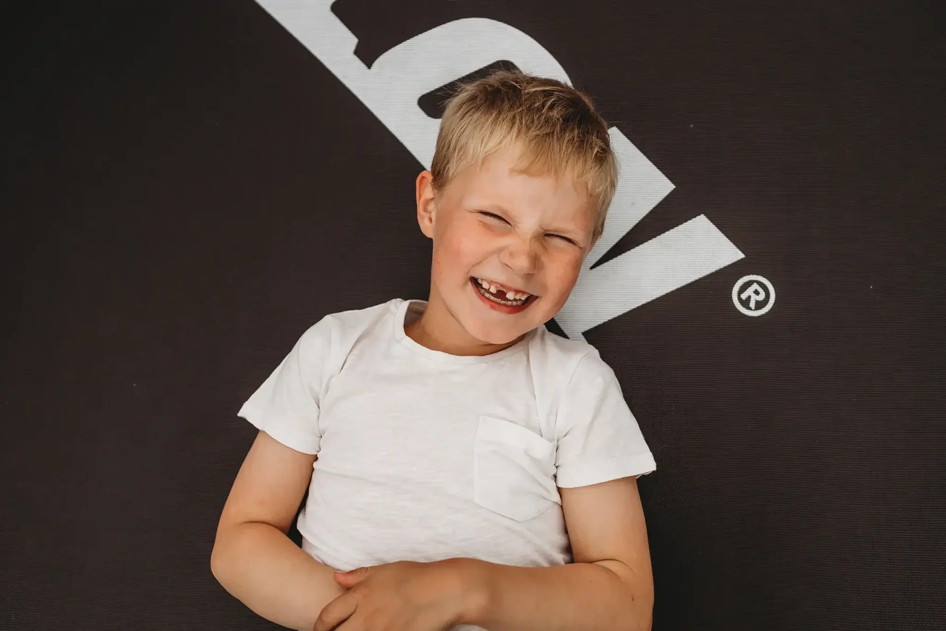 Glücklicher Junge lächelt und liegt auf einem Acon-Trampolin.