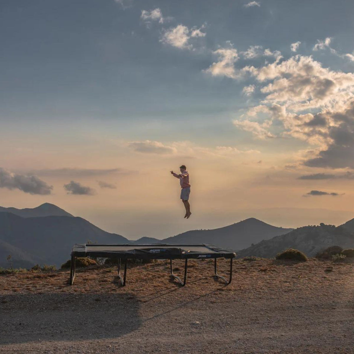 Mann hüpft auf Trampolin im Sonnenuntergang