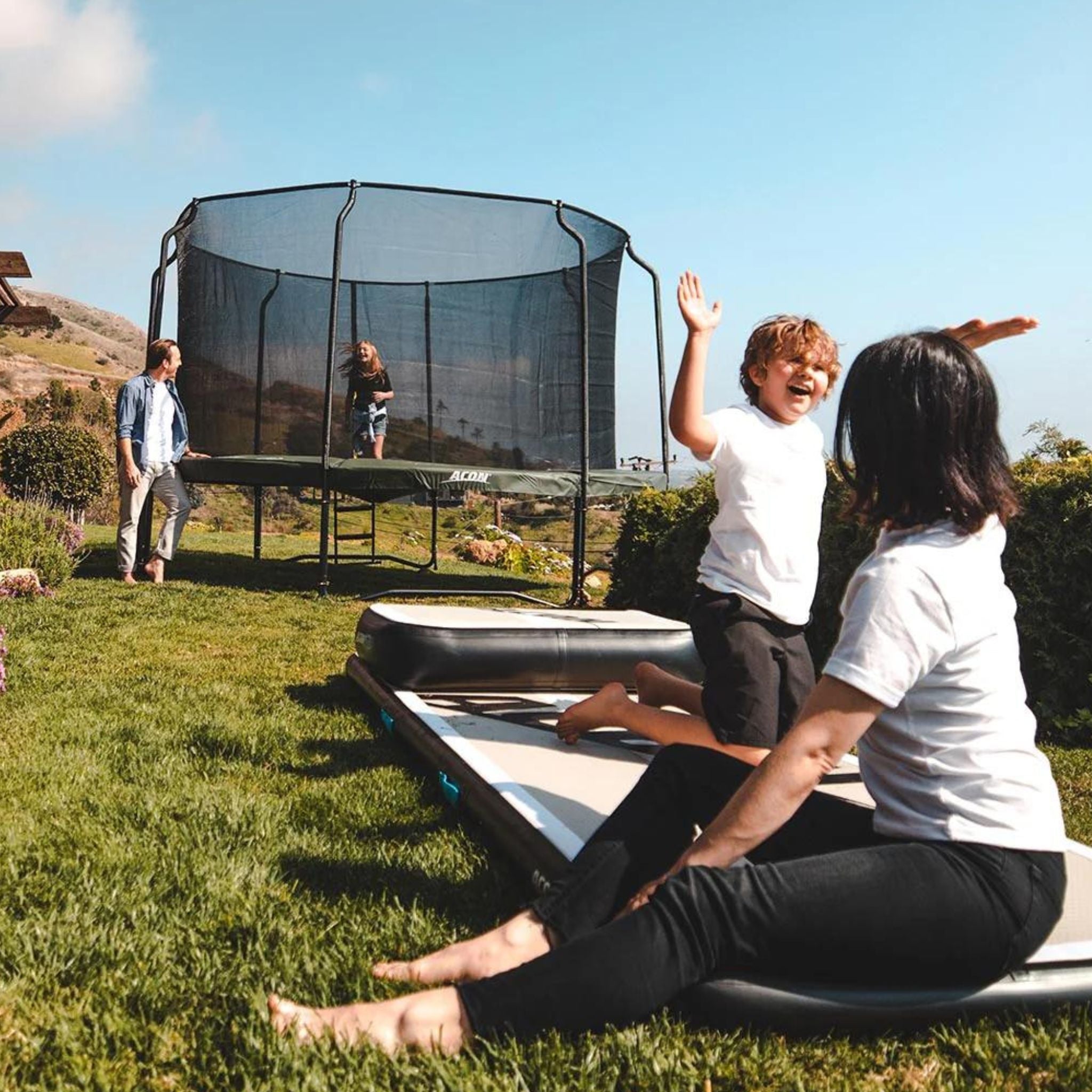 Familie sitzt im Garten auf einer Airtrack Matte