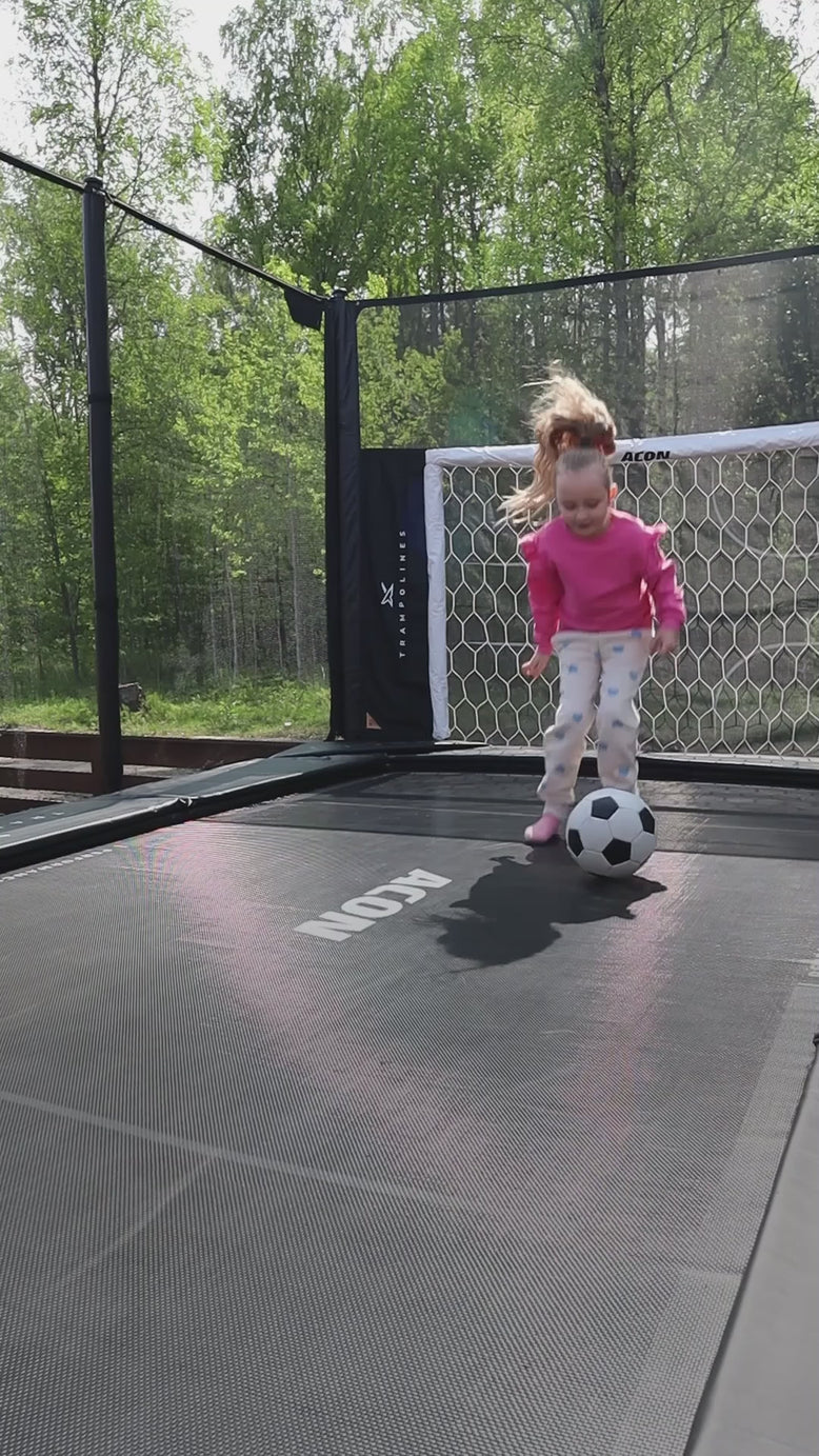 Ein kleines Mädchen springt auf einem Acon X Trampolin und spielt Trampolin-Fußball.