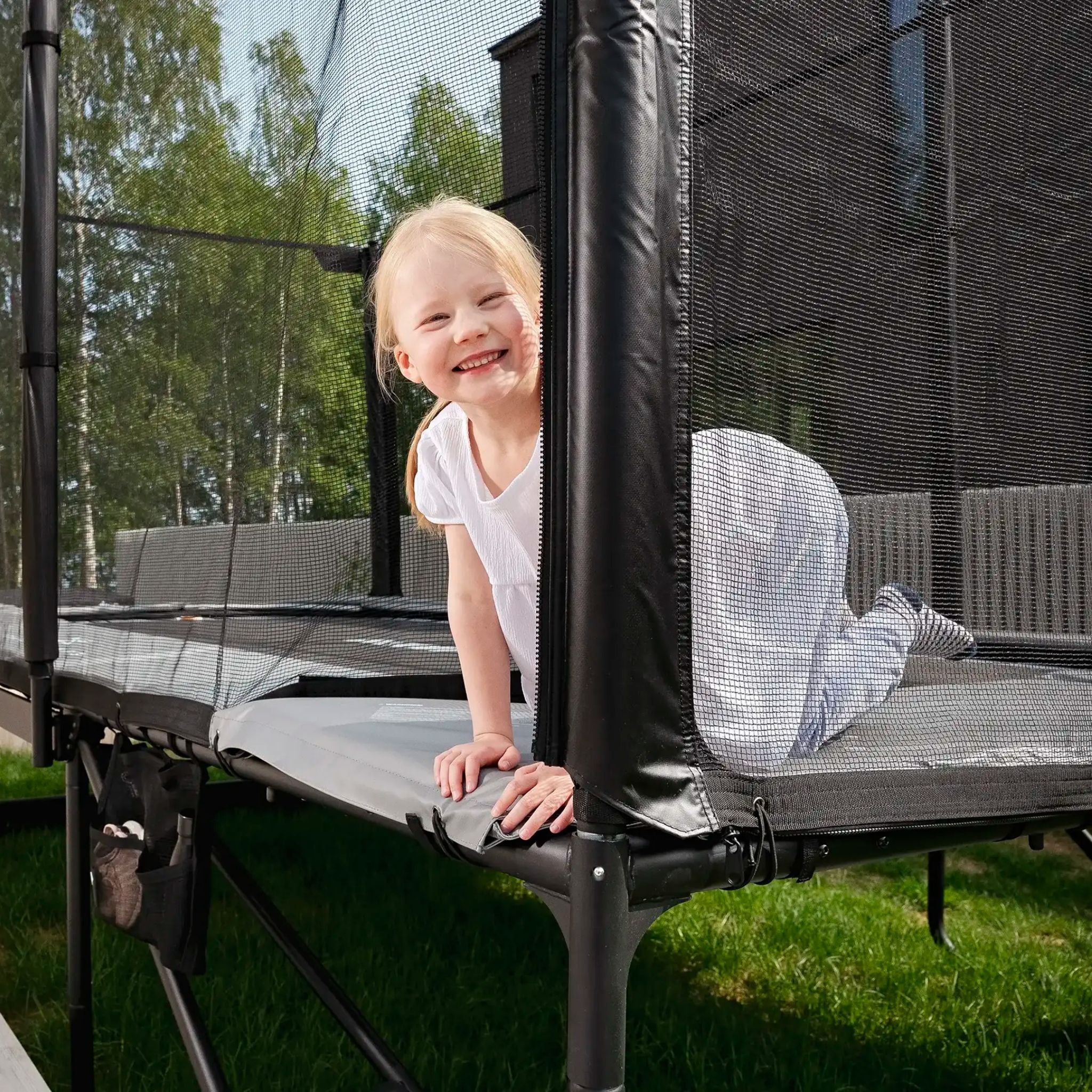 Ein junges Mädchen springt auf einem Trampolin im Garten, das sicher und stabil ist für unbeschwerten Spaß.